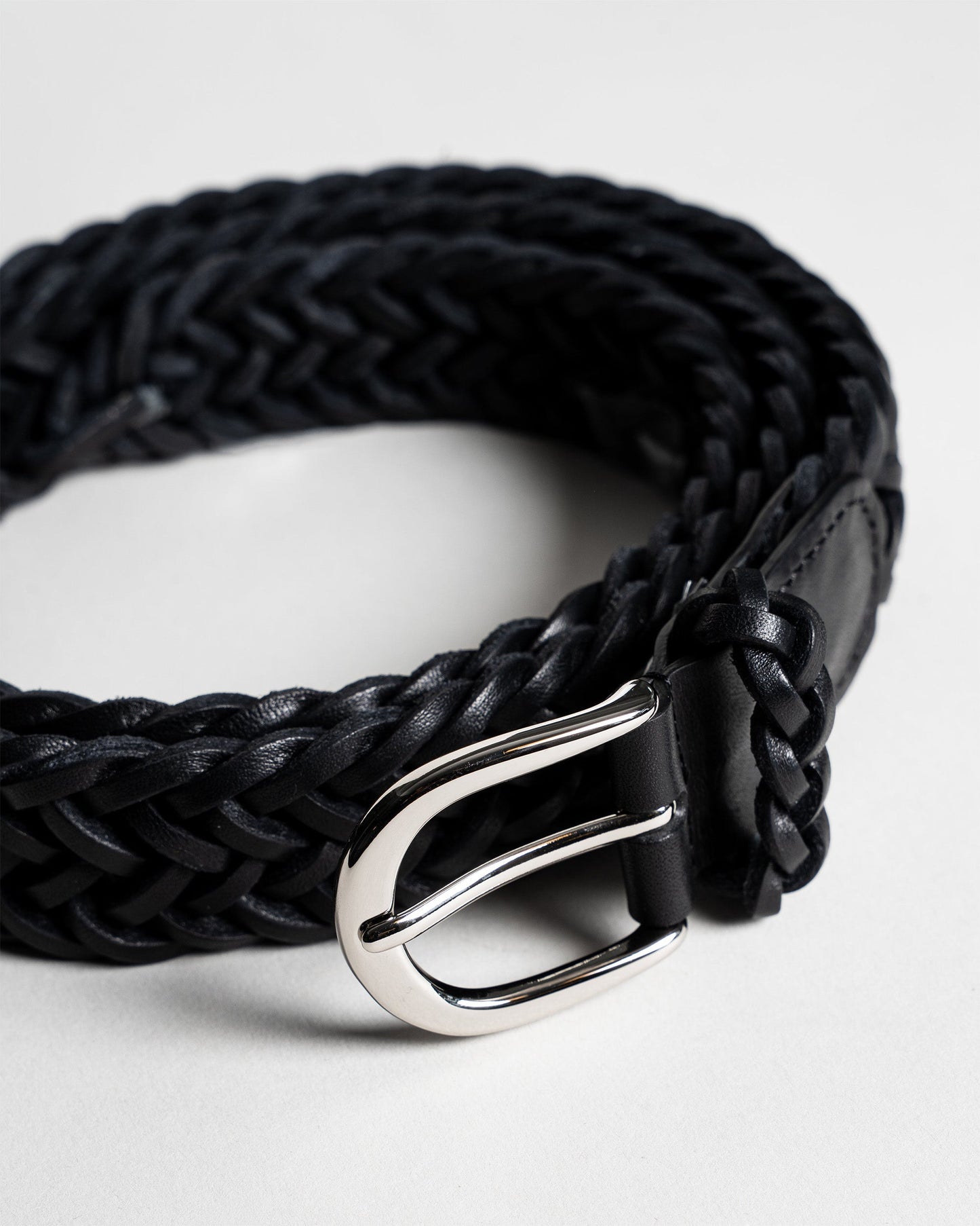 Close-up of the Braided Belt in black leather, highlighting the hand-woven texture and polished silver buckle for a refined, versatile men's accessory.