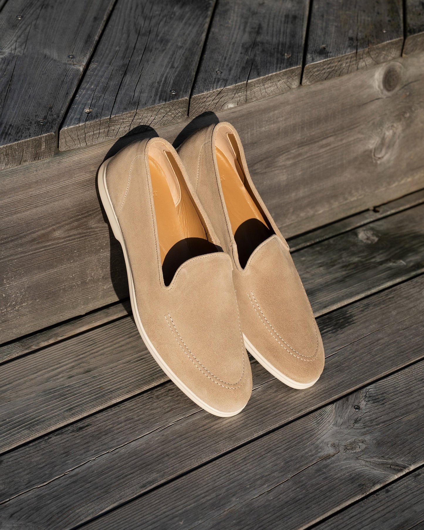 Brännö II in sand suede displayed outdoors on wooden decking, highlighting the soft beige suede upper, clean stitching, and white rubber soles, ideal for relaxed summer occasions.