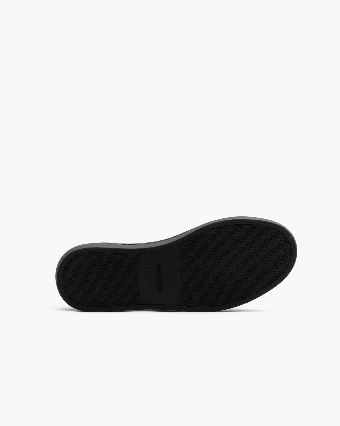 Close-up of the black rubber sole of Alnö Monochrome II in black natural grain, showing the textured tread pattern and subtle MYRQVIST branding at the midfoot.