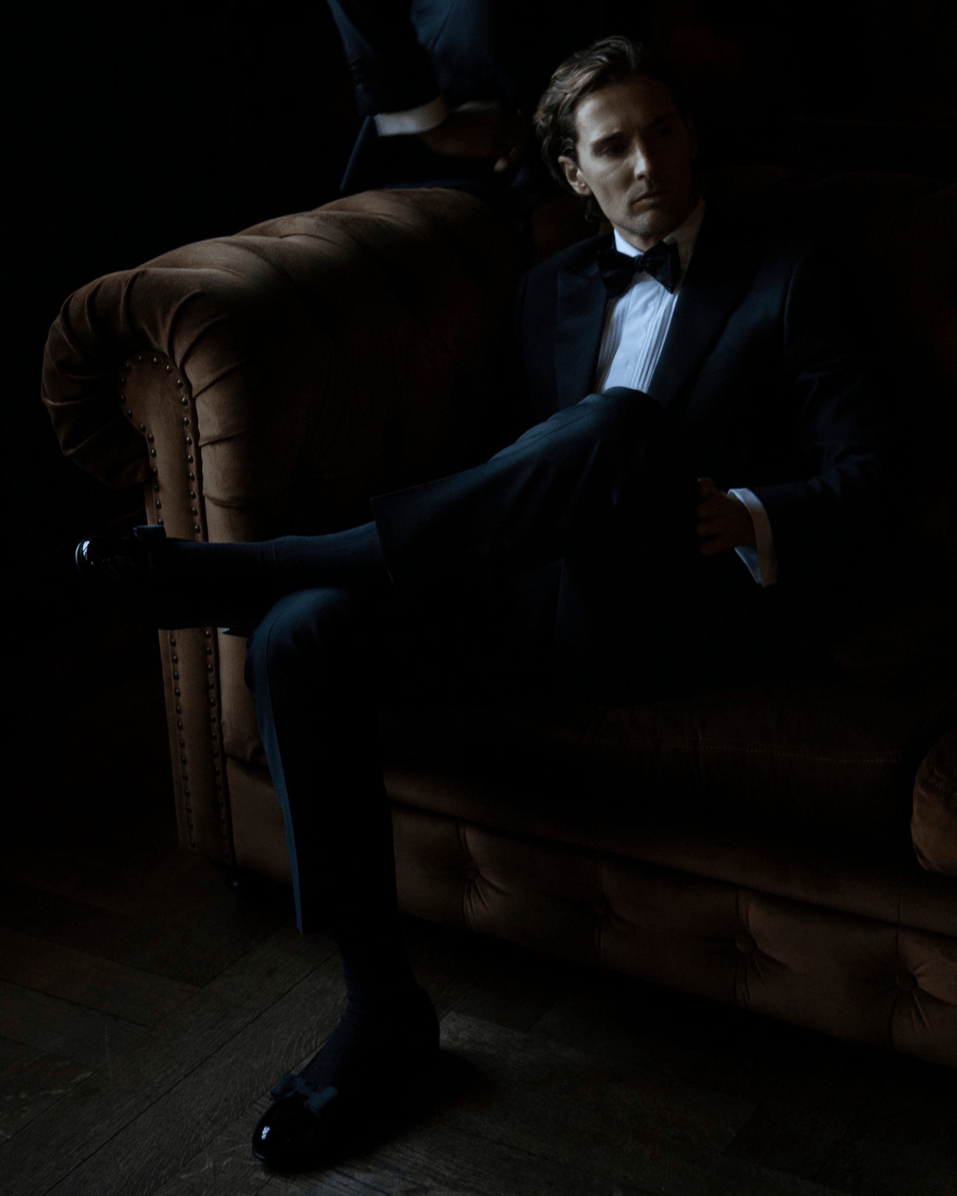 Rosendal in black patent leather worn with a tuxedo and dark socks, highlighting the glossy opera pump silhouette and grosgrain bow, perfect for sophisticated black tie events.