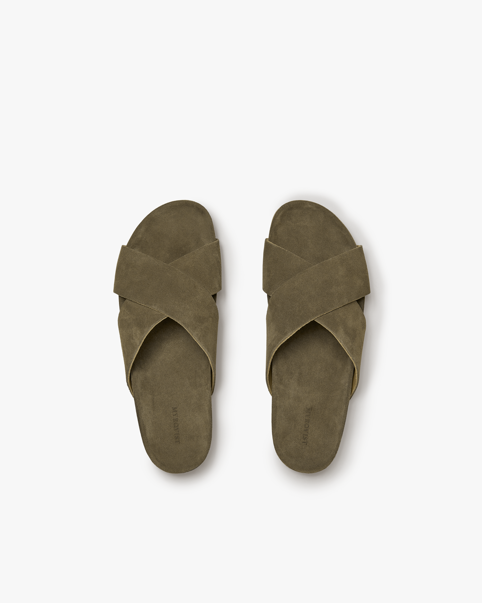 Pair of Solvik men’s sandals in moss green suede, featuring wide cross-over straps and a moulded cork footbed, shown from above to highlight the minimalist, nature-inspired design.