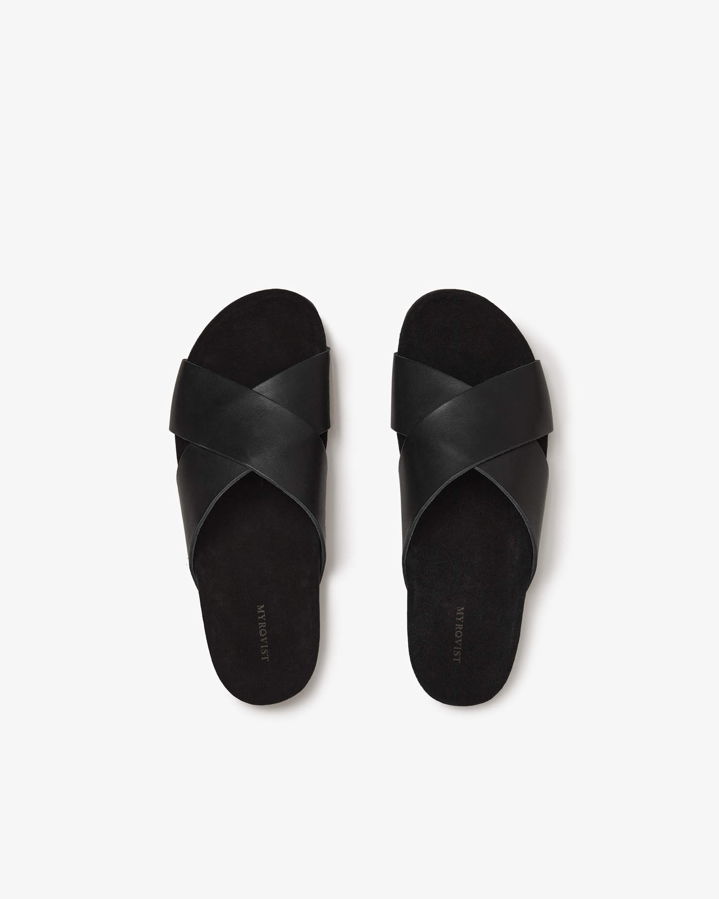 A pair of Solvik sandals in black calf shown from above, featuring wide cross-over leather straps and a soft suede footbed, designed for comfort and understated summer style.