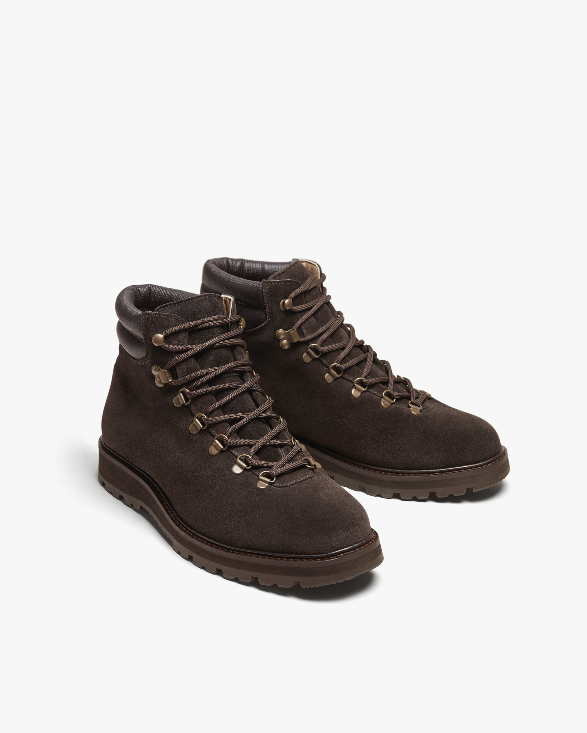 Duved in dark brown suede features a pair of suede hiking boots with brass-toned hardware, padded leather collars, and sturdy lug soles, blending refined style with outdoor-ready durability.