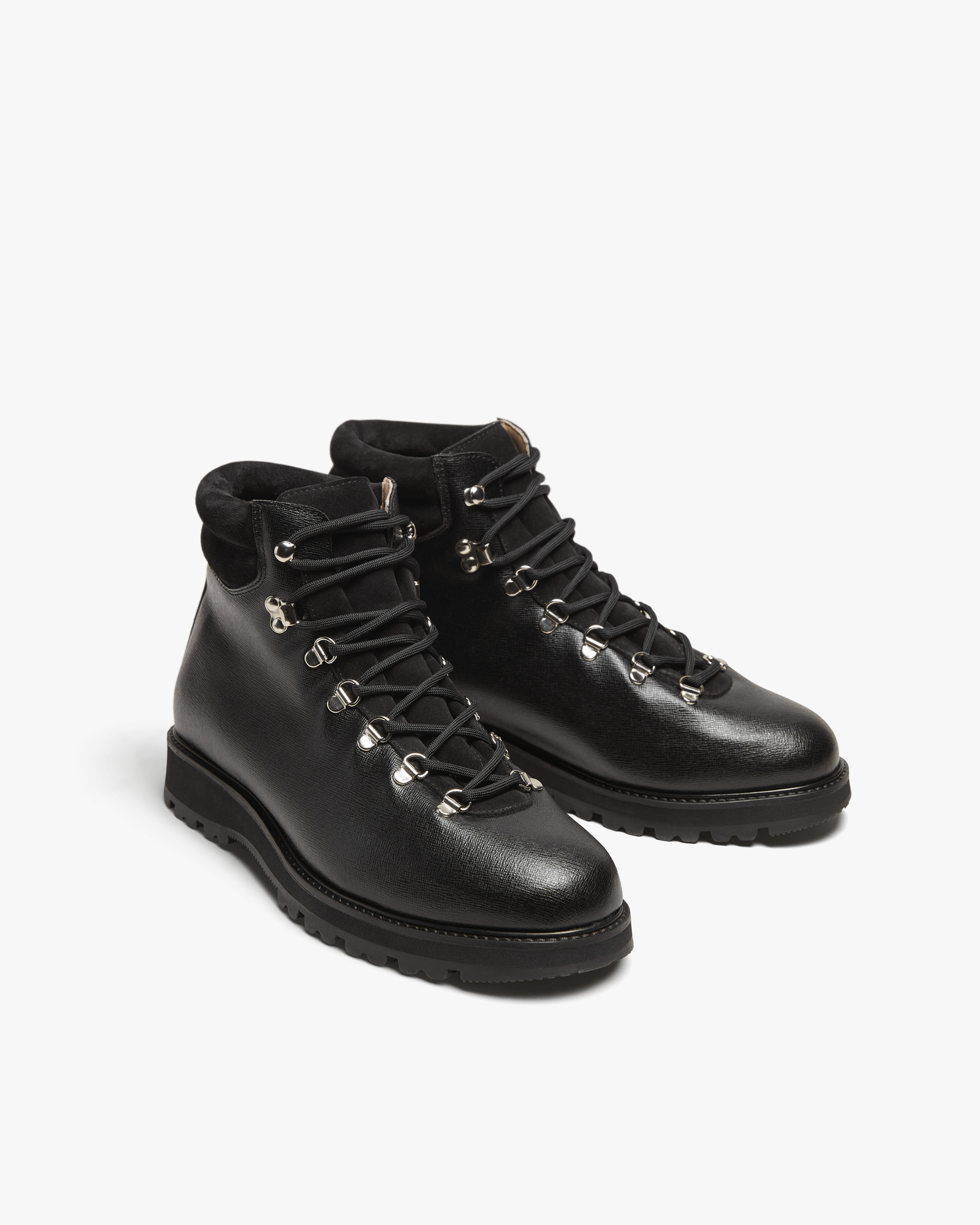 Duved in black grain calf features a crosshatch textured leather upper, silver-toned hardware, padded collars, and sturdy hiking soles, blending refined style with outdoor-ready durability.