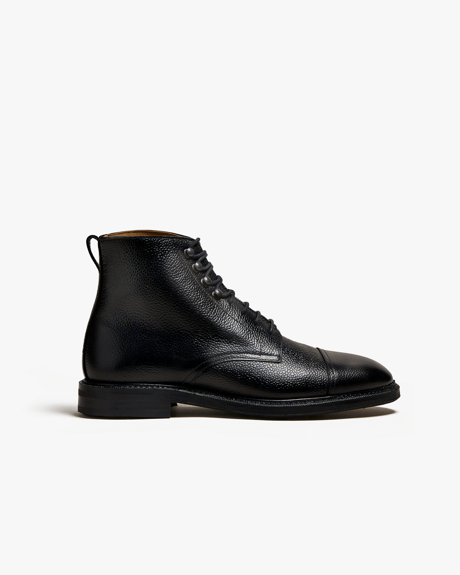 Abisko in black country calf features a grained leather upper with a cap toe, lace-up closure, and pull tab, set on a sturdy rubber sole for versatile wear with wool trousers or denim.