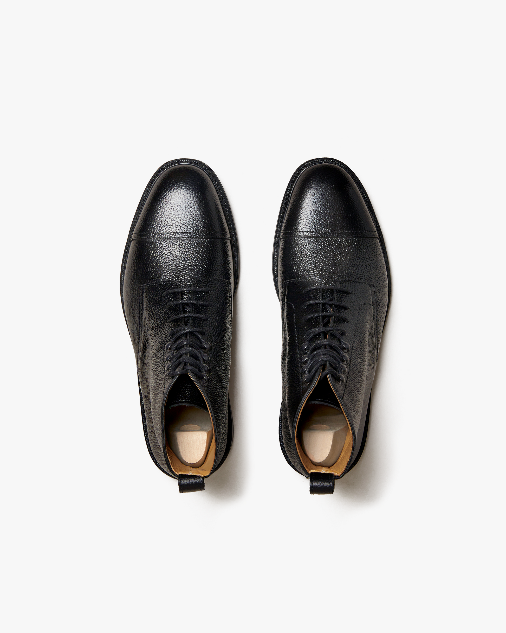 Abisko in black country calf shown from above, highlighting the grained leather upper, cap toe, lace-up closure, and structured silhouette ideal for pairing with wool trousers or denim.
