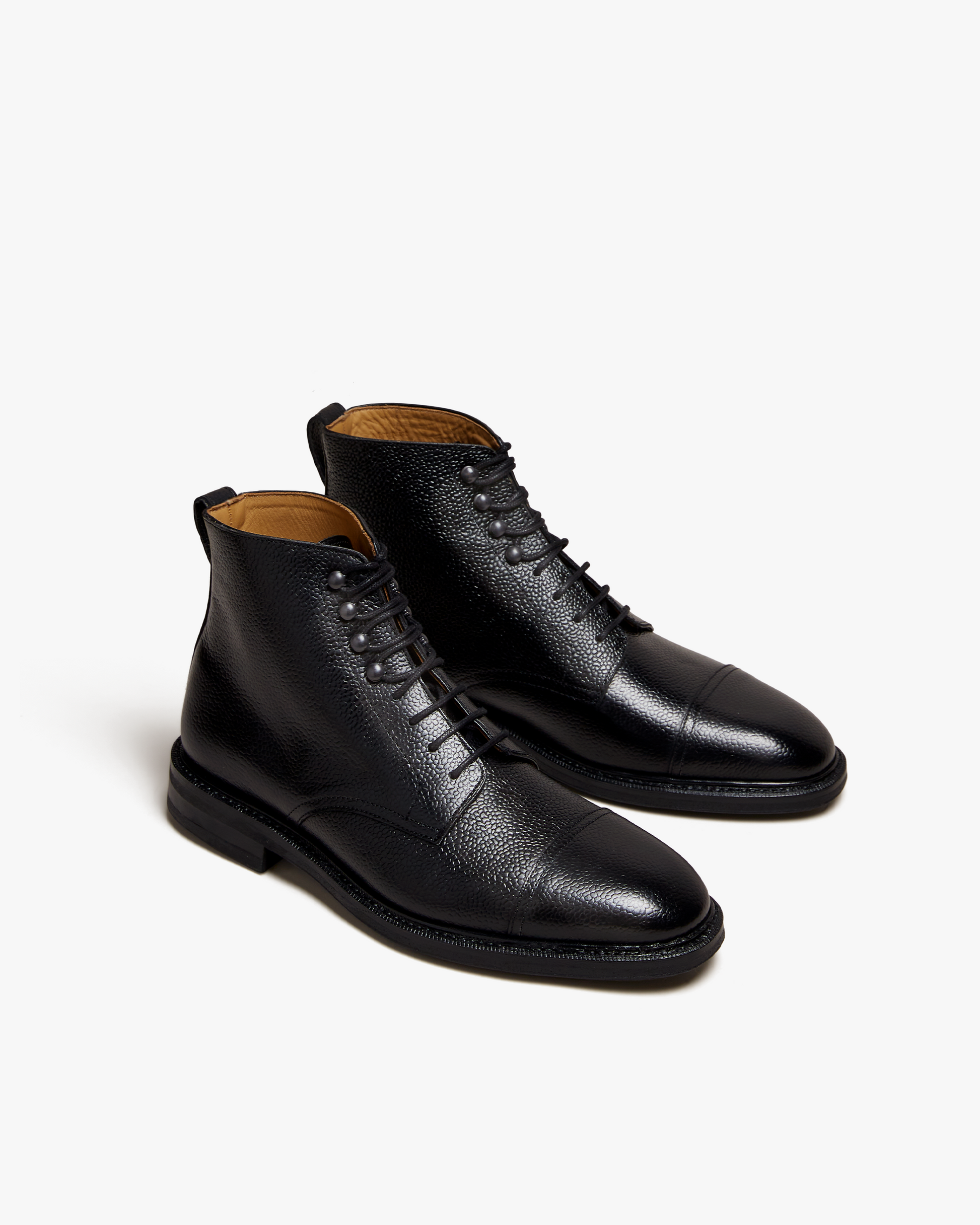 Abisko in black country calf features a grained leather upper, cap toe, and lace-up closure, offering a structured silhouette suitable for pairing with wool trousers or denim.