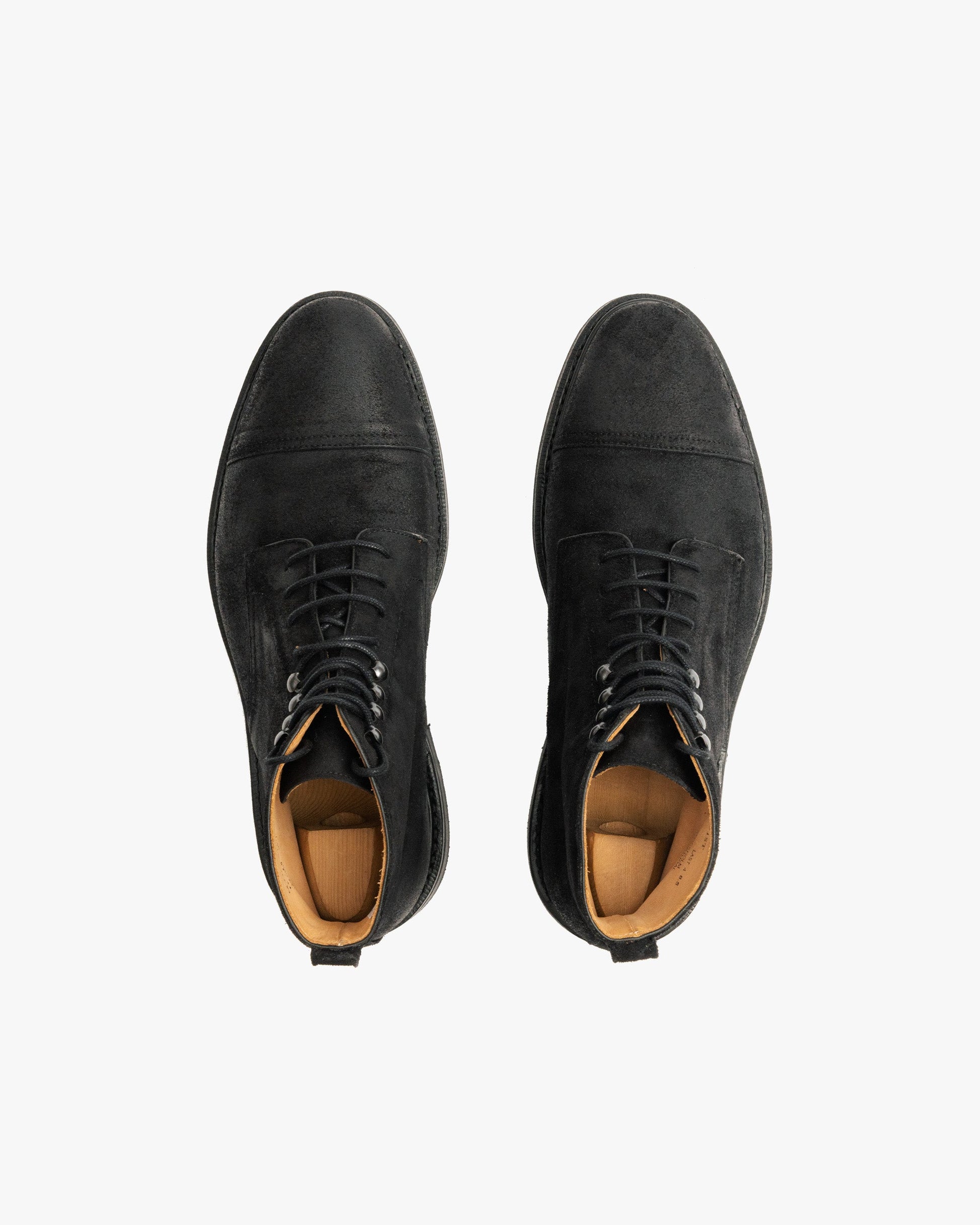 Abisko in black waxed suede shown from above, highlighting the matte black cap toe boots with lace-up closure, subtle stitching, and tan leather lining.