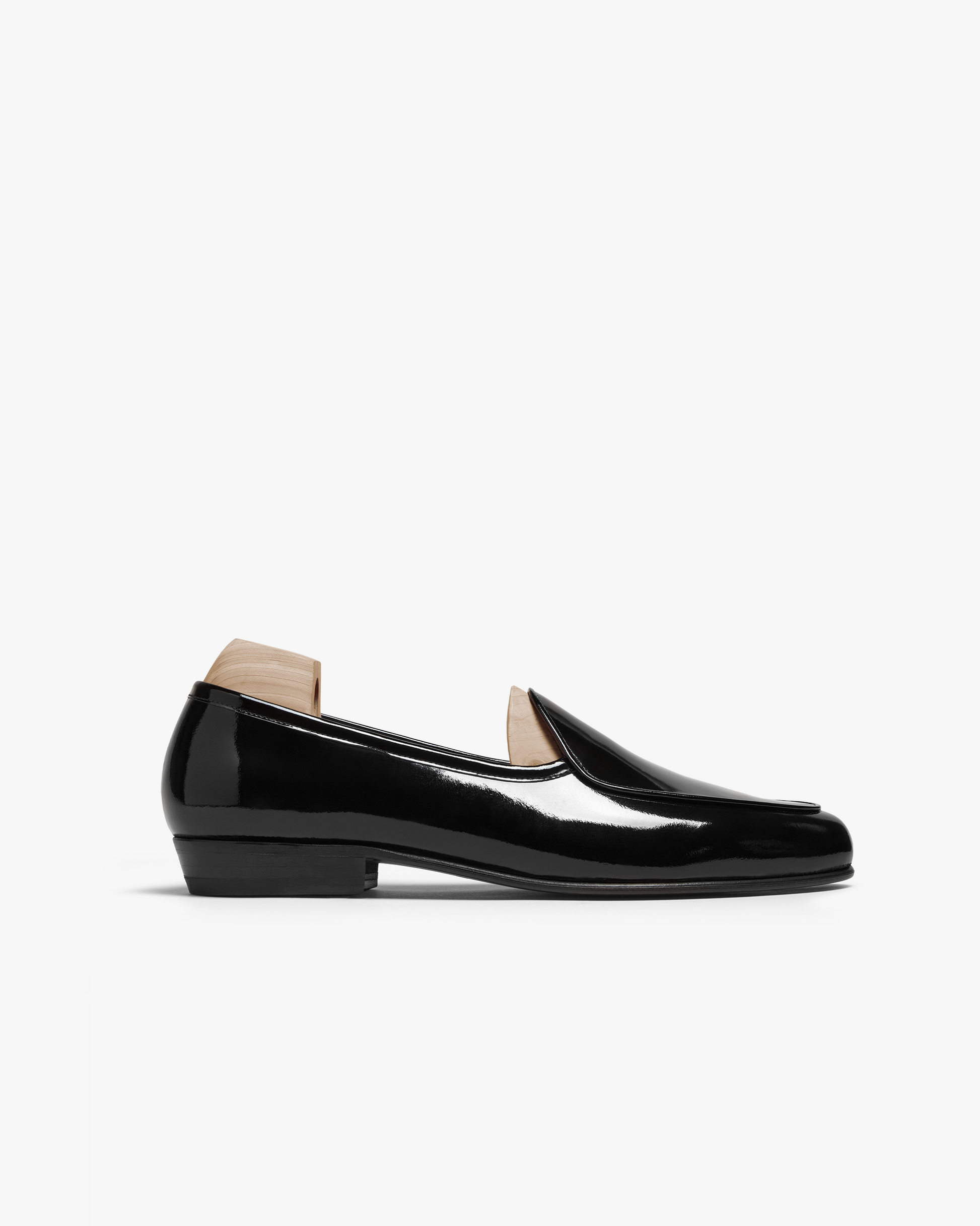 Ängby loafer in black patent leather with a sleek, mirror-like finish, gently rounded toe, and subtle piping, shown in a side profile against a white background.