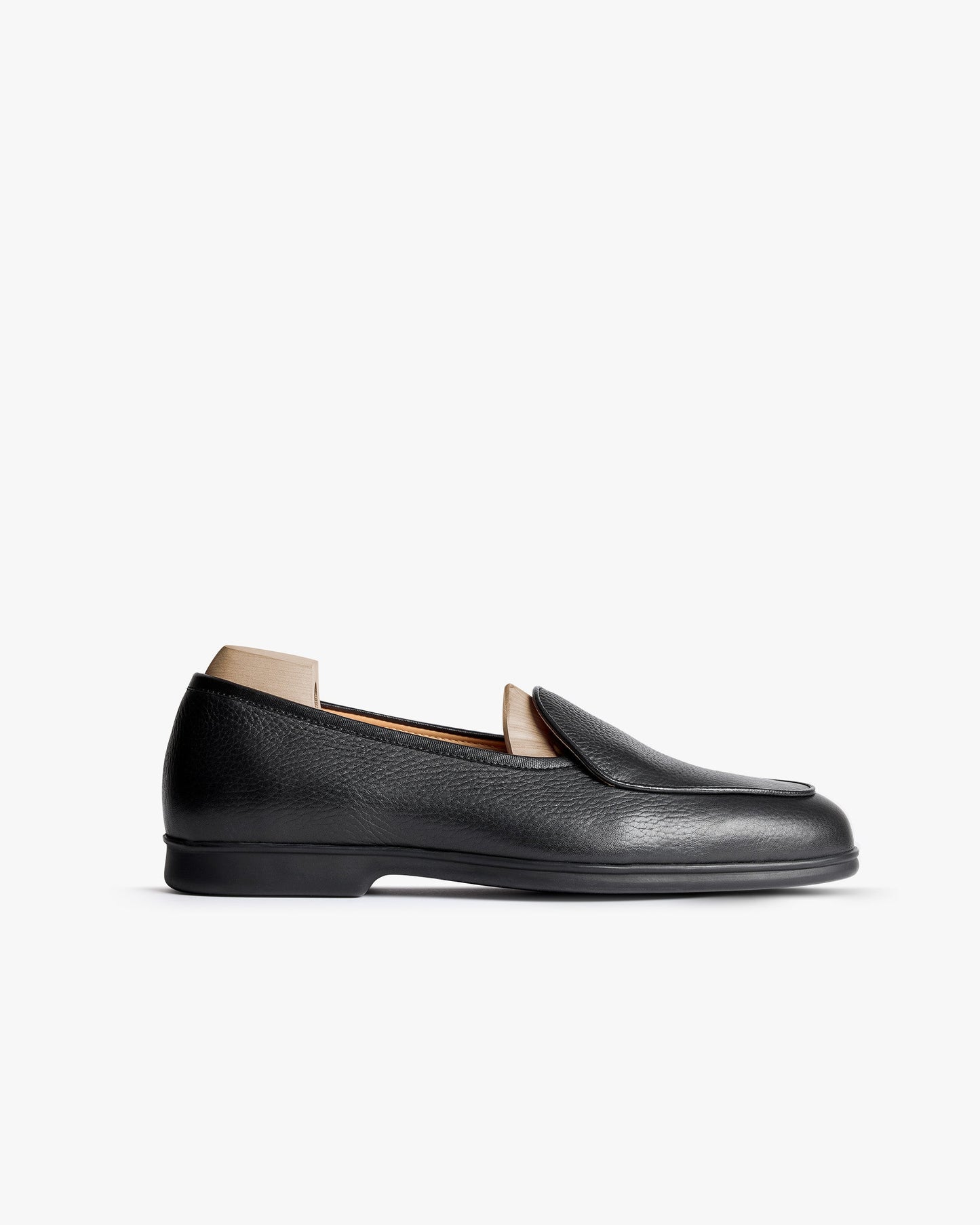 Ängby Walker in black grain calf features a minimalist loafer silhouette with softly pebbled leather, a gently rounded toe, and a low-profile rubber sole, shown in a side view against a clean white background.
