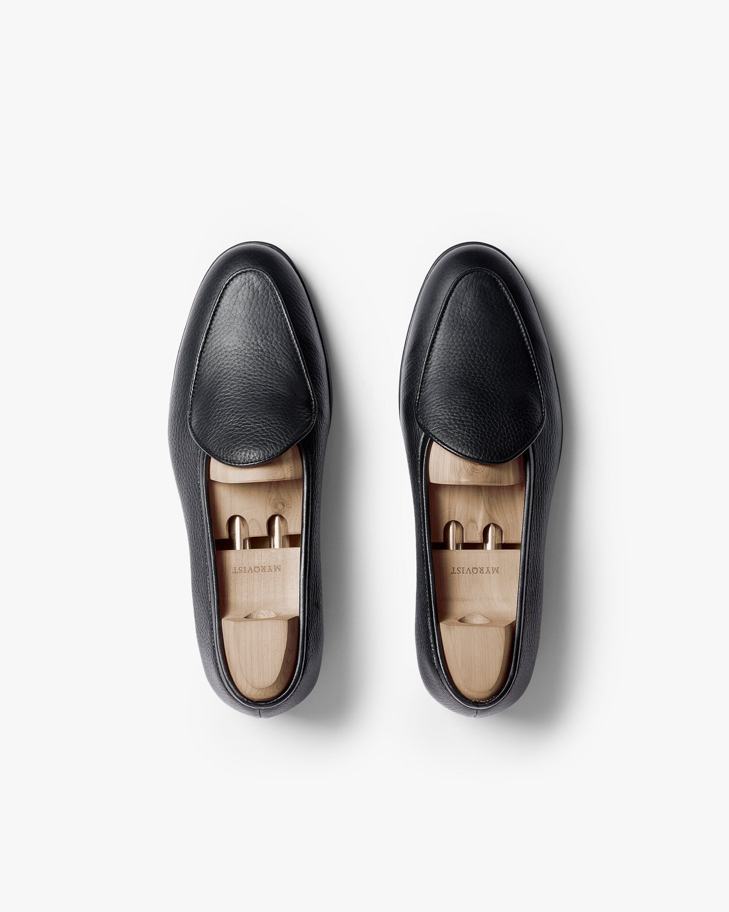 Ängby Walker in black grain calf shown from above as a pair, featuring softly pebbled leather uppers, seamless aprons, and wooden shoe trees set against a clean white background.