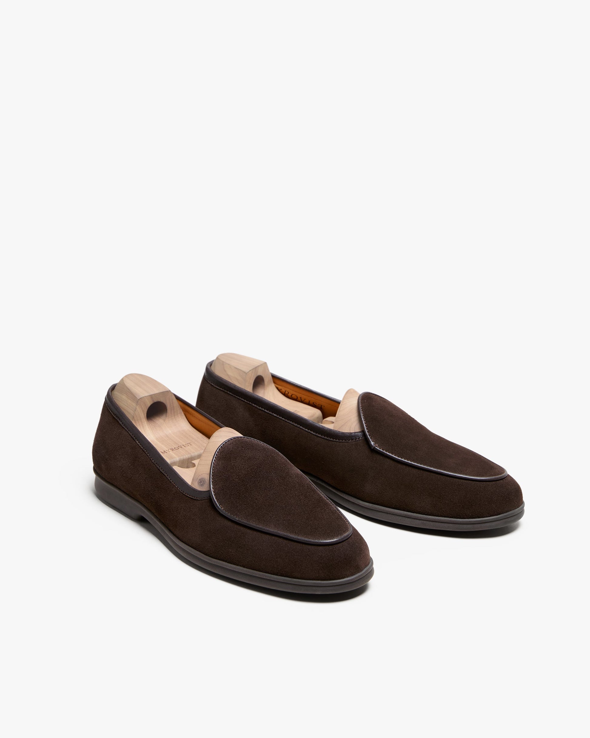 Ängby Walker in dark brown suede displayed at an angle, showing the soft suede texture, clean piping along the apron, and sturdy rubber soles, with wooden shoe trees maintaining the loafer shape.