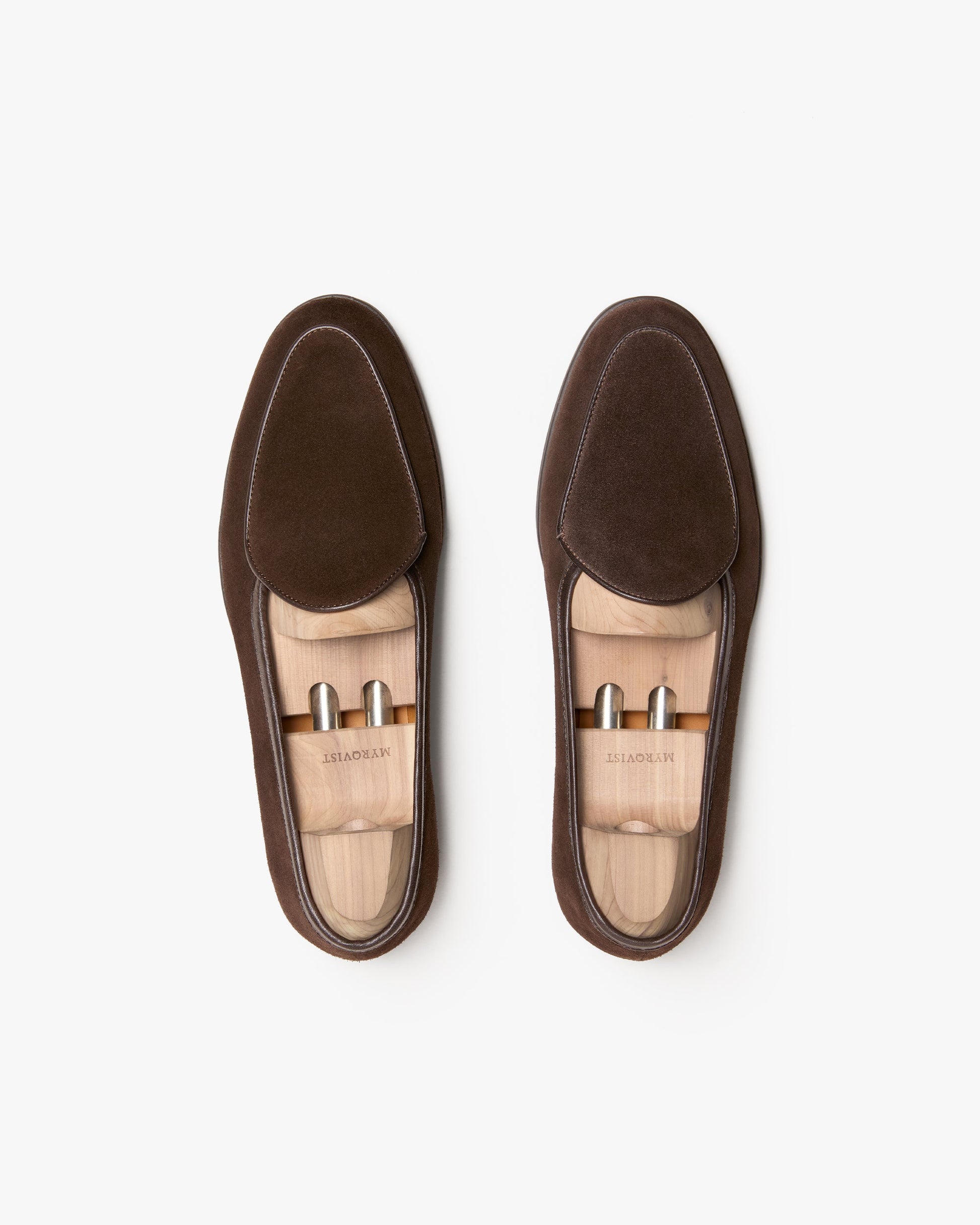 Pair of Ängby Walker in dark brown suede shown from above, highlighting the clean lines, softly rounded toe, subtle piping, and wooden shoe trees inside each loafer.