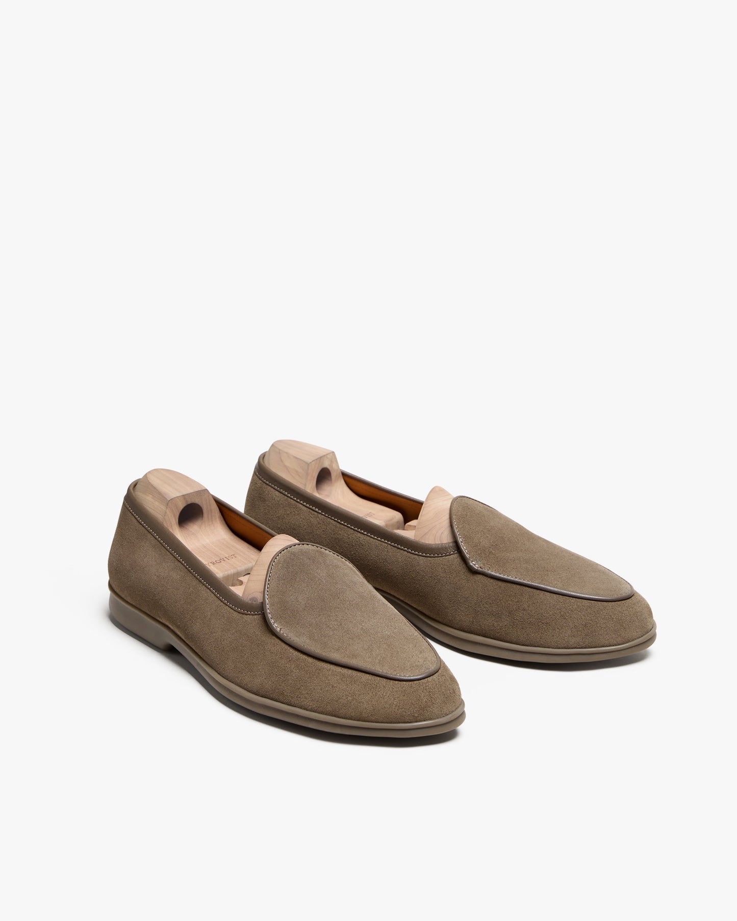 Ängby Walker in taupe suede shown at an angle, highlighting the soft suede texture, minimalist Belgian loafer silhouette, subtle piping, and supportive rubber sole with wooden shoe trees inside.
