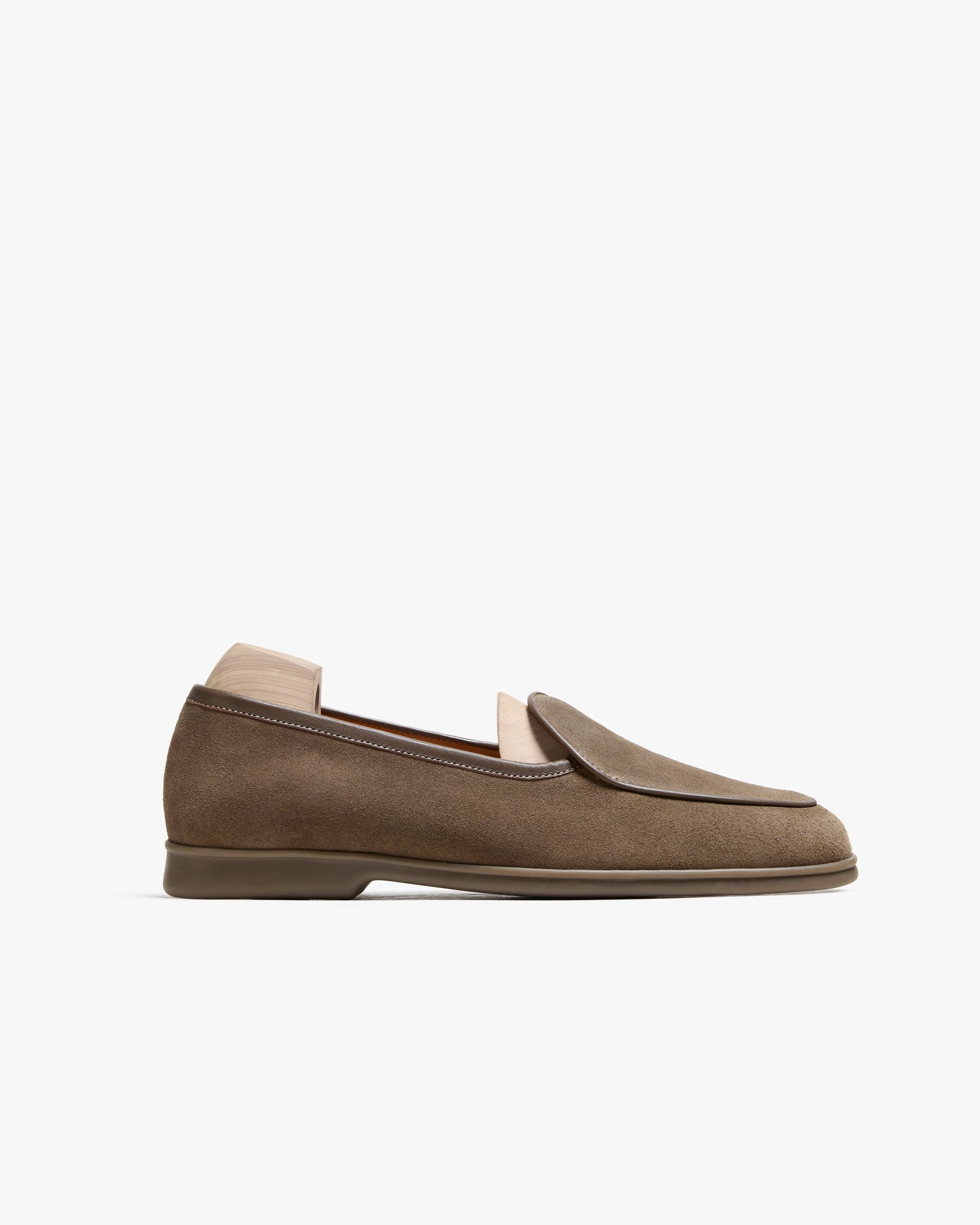 Ängby Walker in taupe suede features a minimalist Belgian loafer silhouette with soft suede, subtle piping, and a gently rounded toe, set on a cushioned rubber sole for comfort and versatility. The understated taupe shade and clean design make it ideal for pairing with summer trousers or relaxed slacks for both casual and refined occasions.