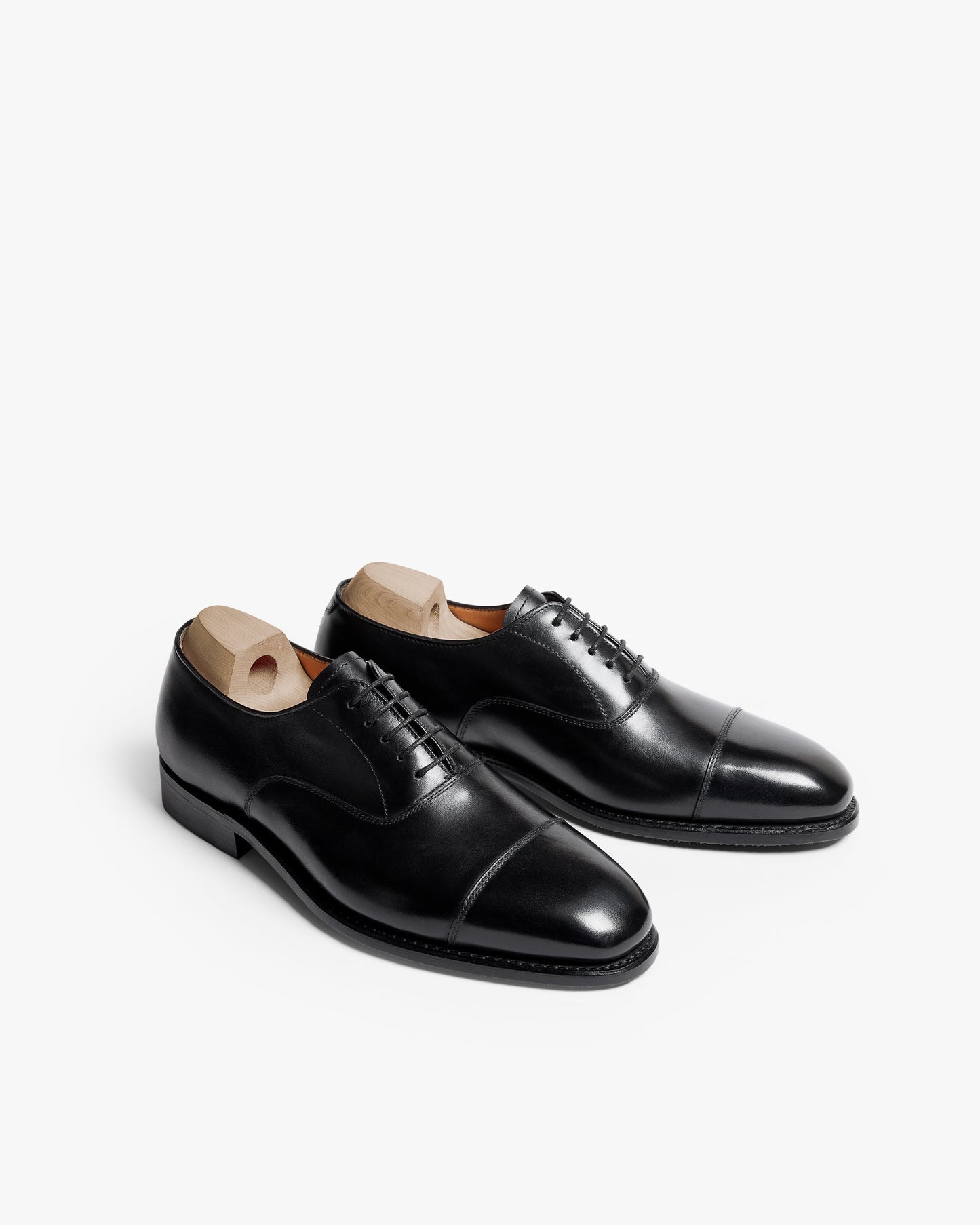 Äppelviken II in black calf, shown at an angle, displays the polished cap-toe Oxford silhouette with closed lacing, subtle stitching, and wooden shoe trees that help preserve the elegant structure.