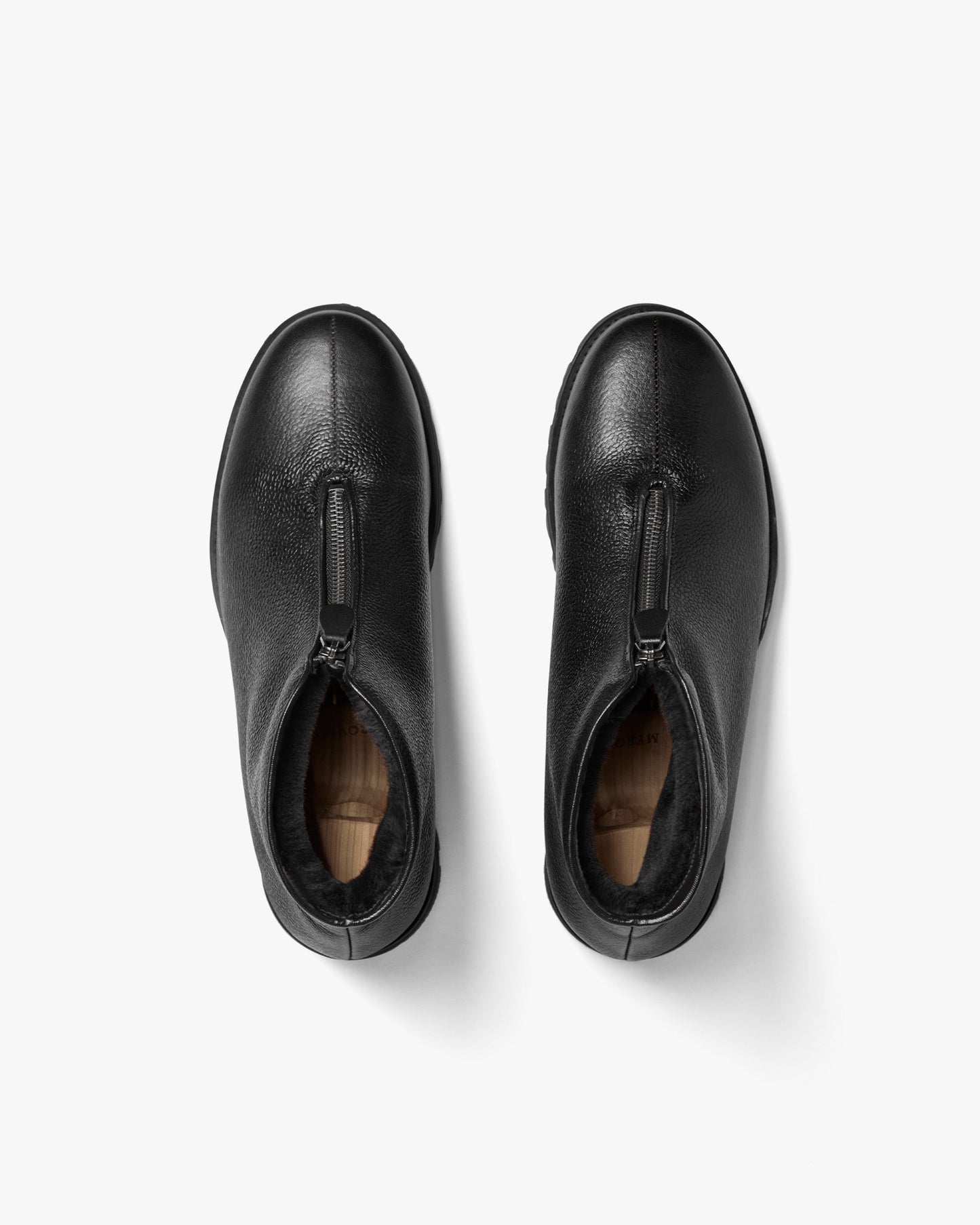 Funäs in black country calf shown from above, highlighting the central zipper, textured full-grain leather, and plush shearling lining for warmth and comfort.