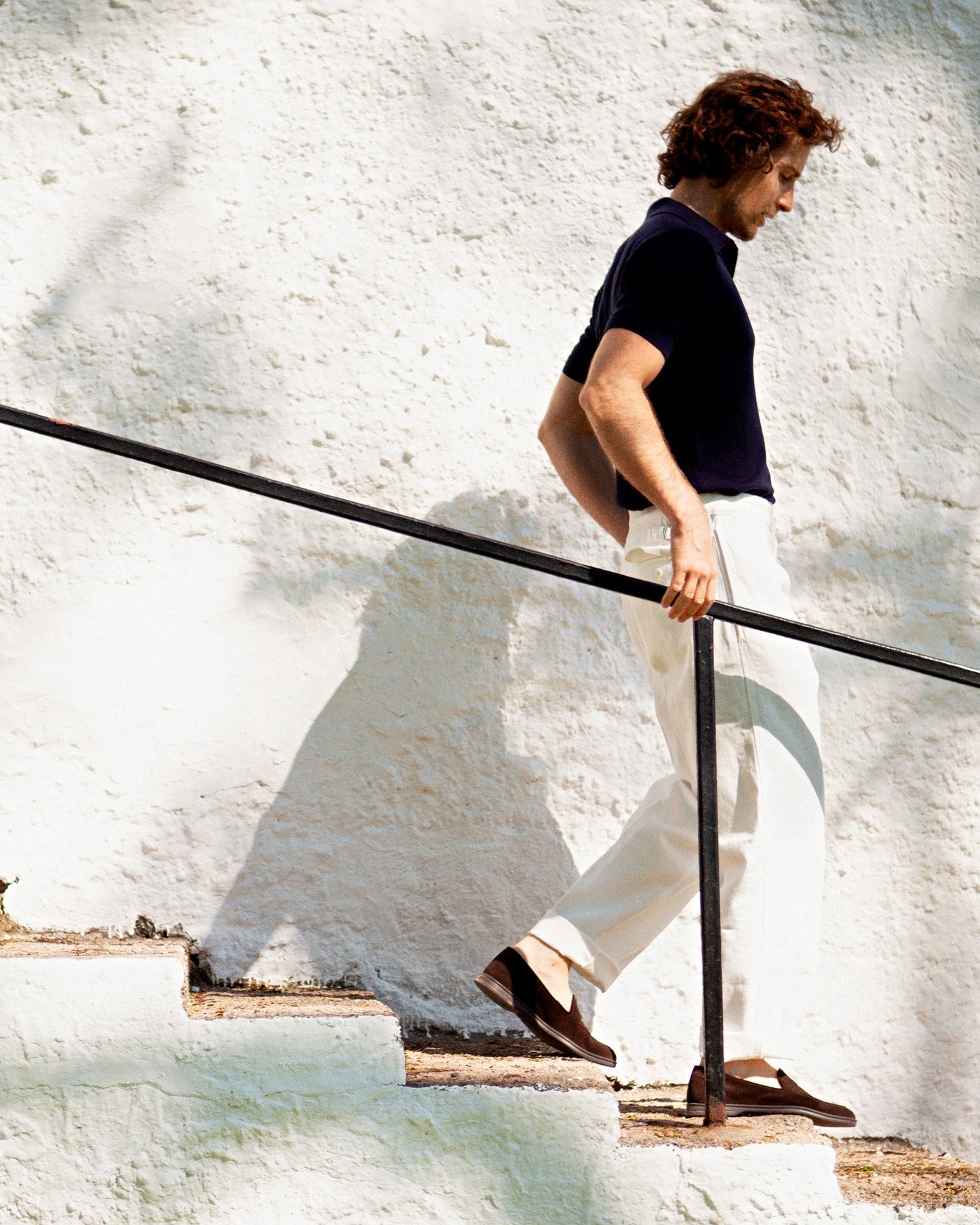 Brännö II in dark brown suede styled with light linen trousers and a dark polo shirt, capturing the loafer's refined silhouette and versatility for warm-weather occasions.