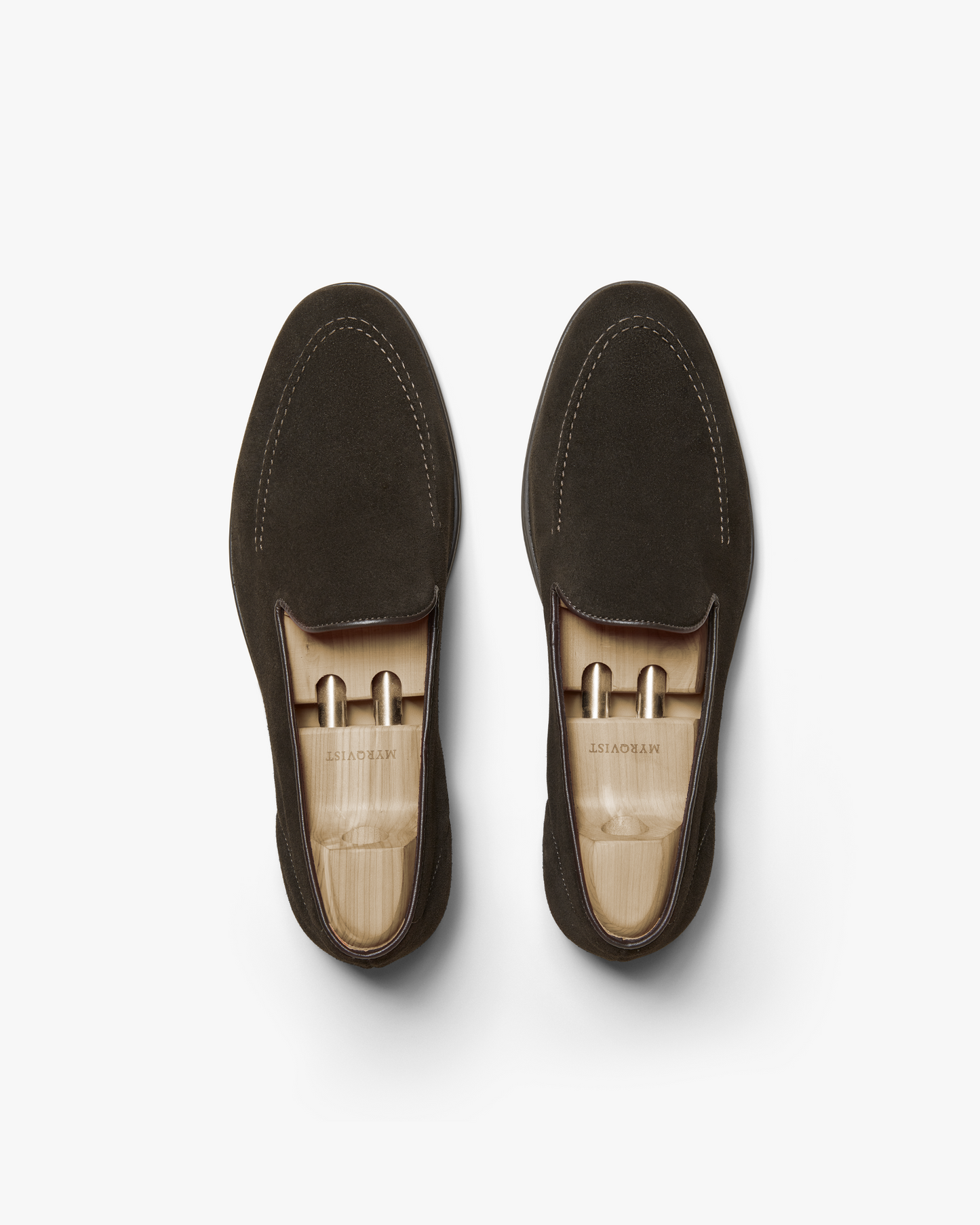 A pair of Brännö II in dark brown suede shown from above, highlighting the clean lines, subtle stitching, and wooden shoe trees that help maintain the loafer's refined shape.