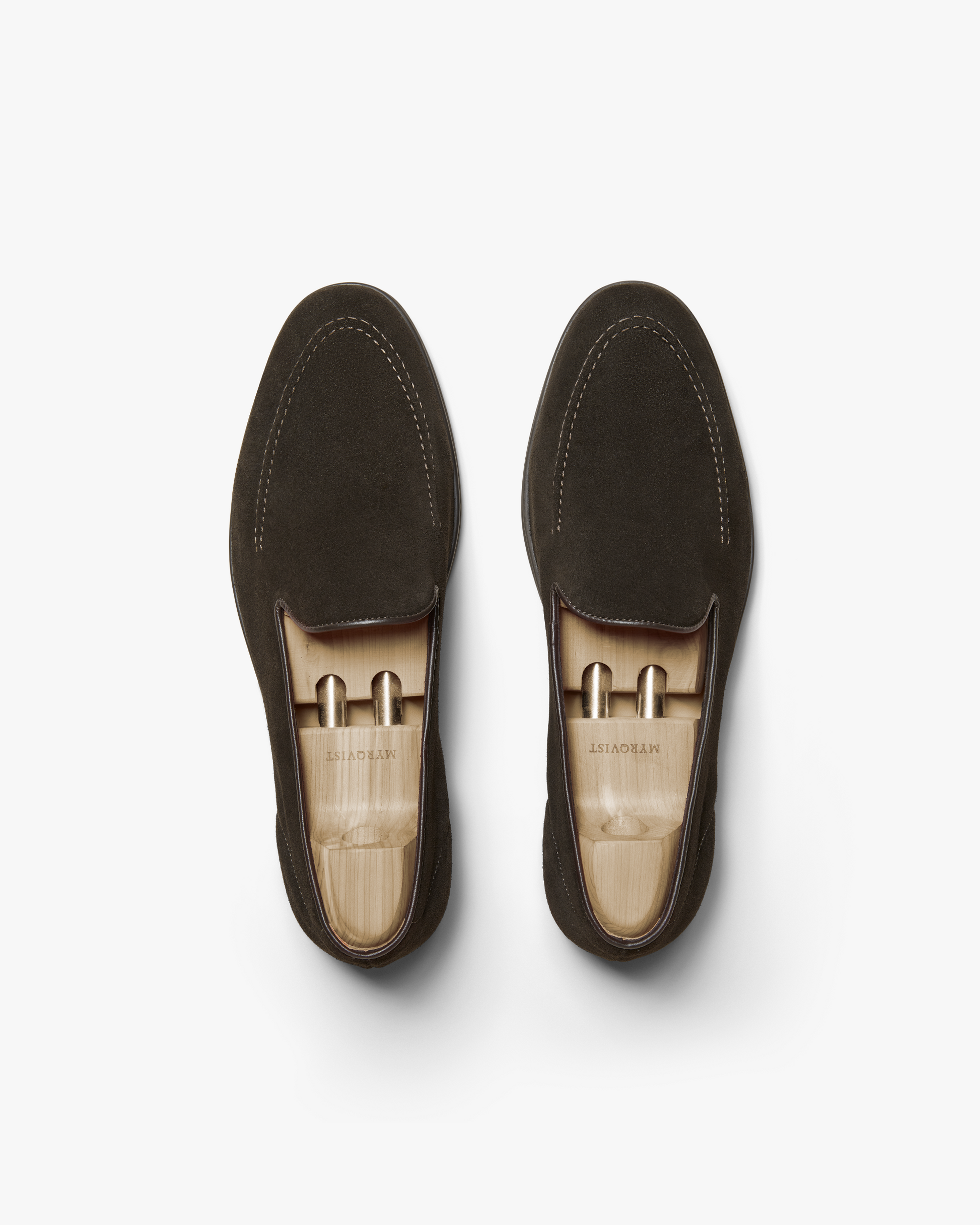 A pair of Brännö II in dark brown suede shown from above, highlighting the clean lines, subtle stitching, and wooden shoe trees that help maintain the loafer's refined shape.