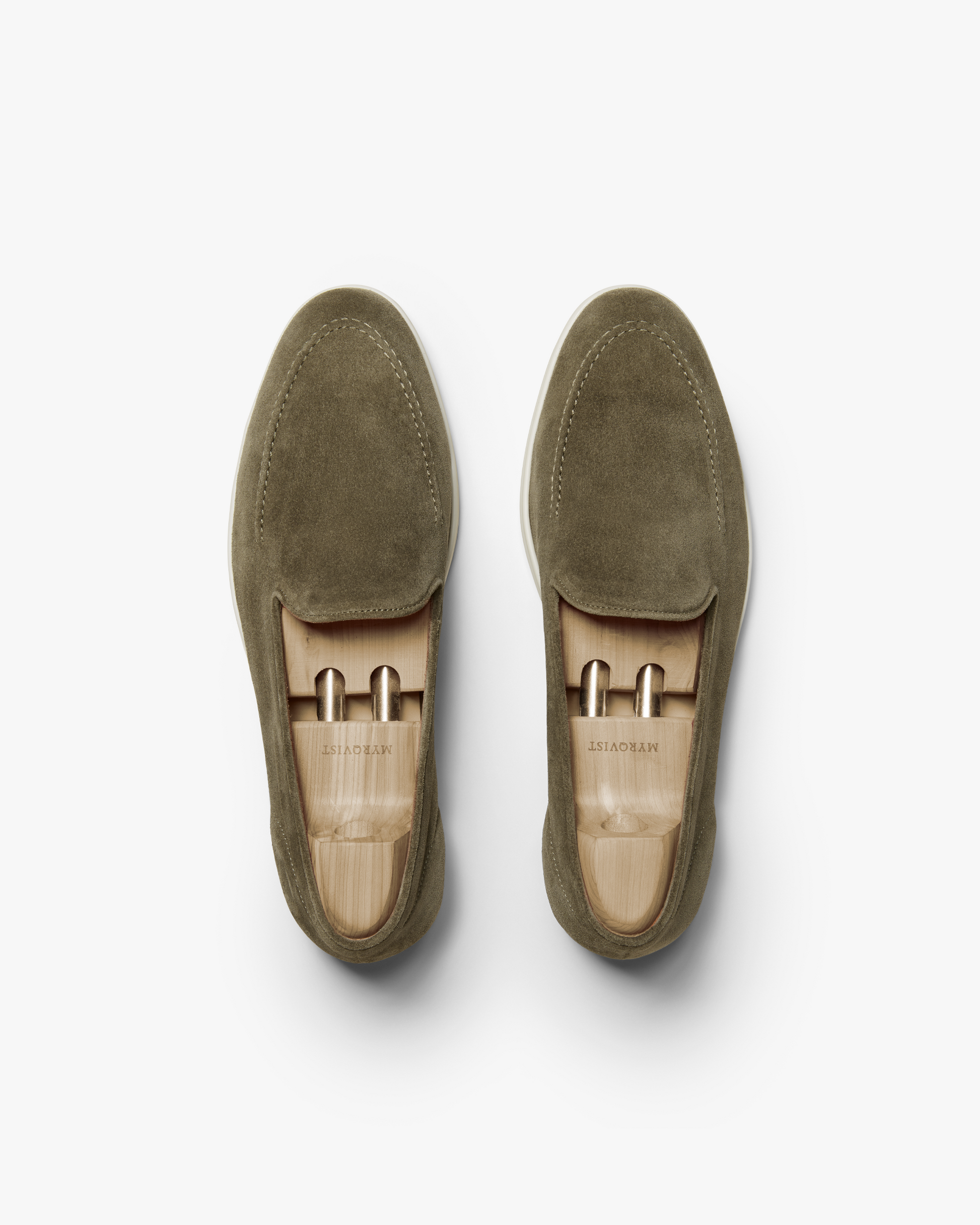 Brännö II in moss green suede shown from above, highlighting the clean lines, tonal stitching, and soft suede texture, with wooden shoe trees maintaining the loafer's shape.