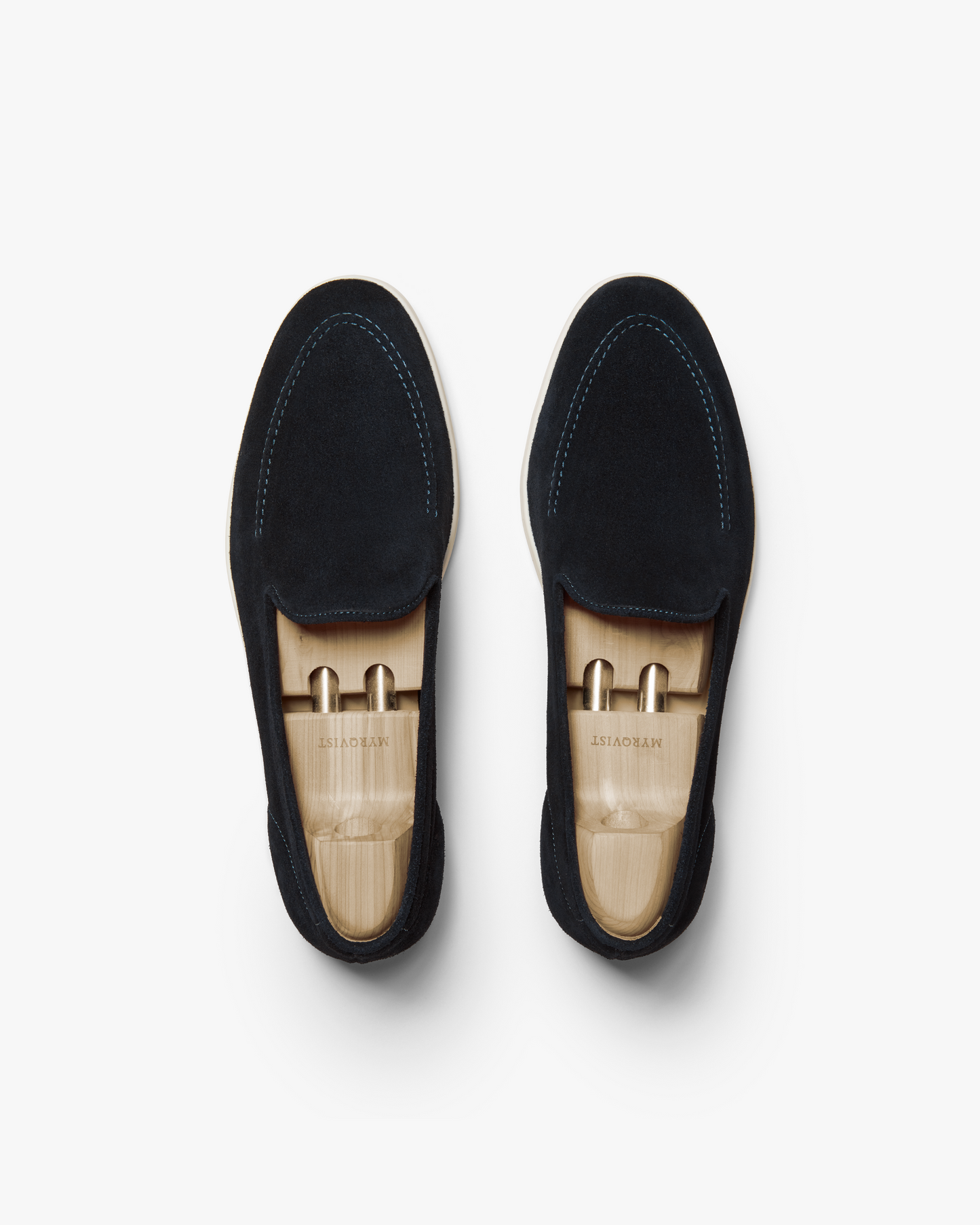 Brännö II in navy suede shown from above, highlighting the soft suede uppers, tonal stitching, and white rubber soles, each loafer fitted with a wooden shoe tree for shape retention.