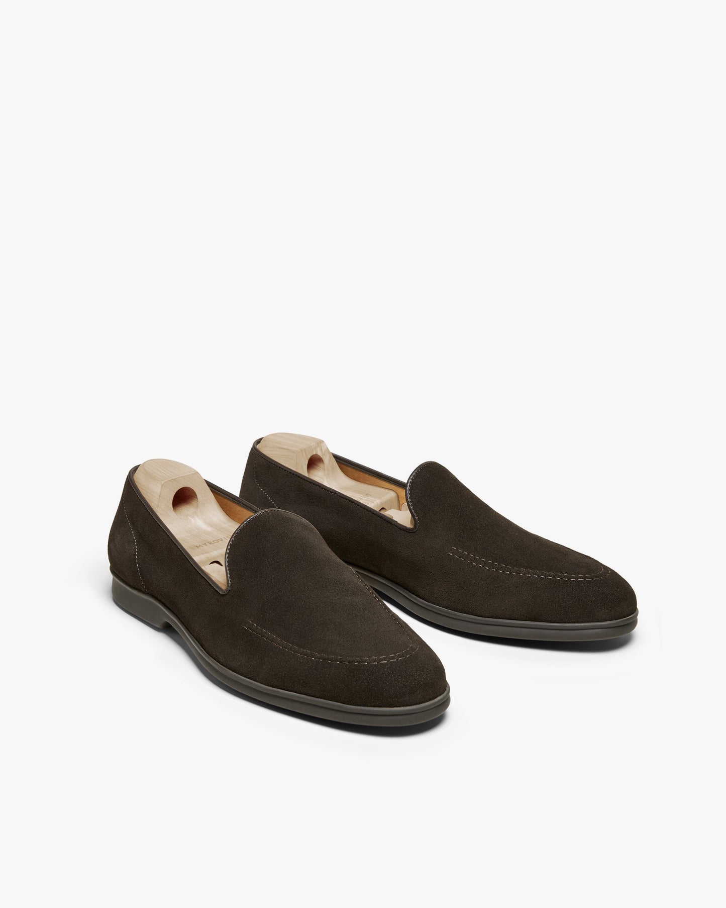 Brännö II in dark brown suede displays a pair of men's suede loafers with a clean, minimalist silhouette, subtle stitching, and wooden shoe trees maintaining their shape.
