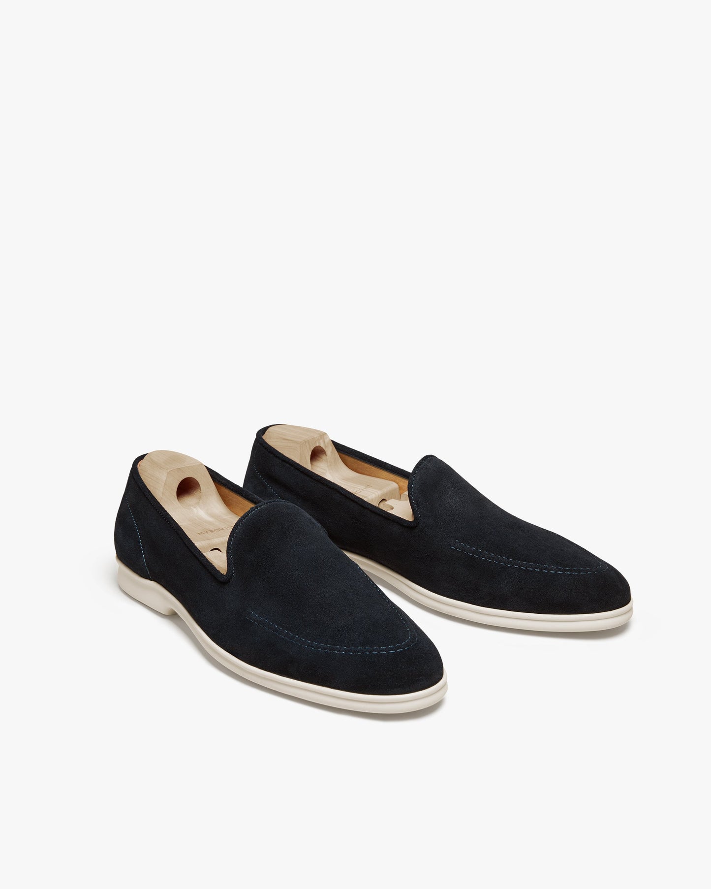 Brännö II in navy suede displayed at an angle, featuring soft suede uppers, tonal stitching, and white rubber soles, each loafer shaped with a wooden shoe tree.