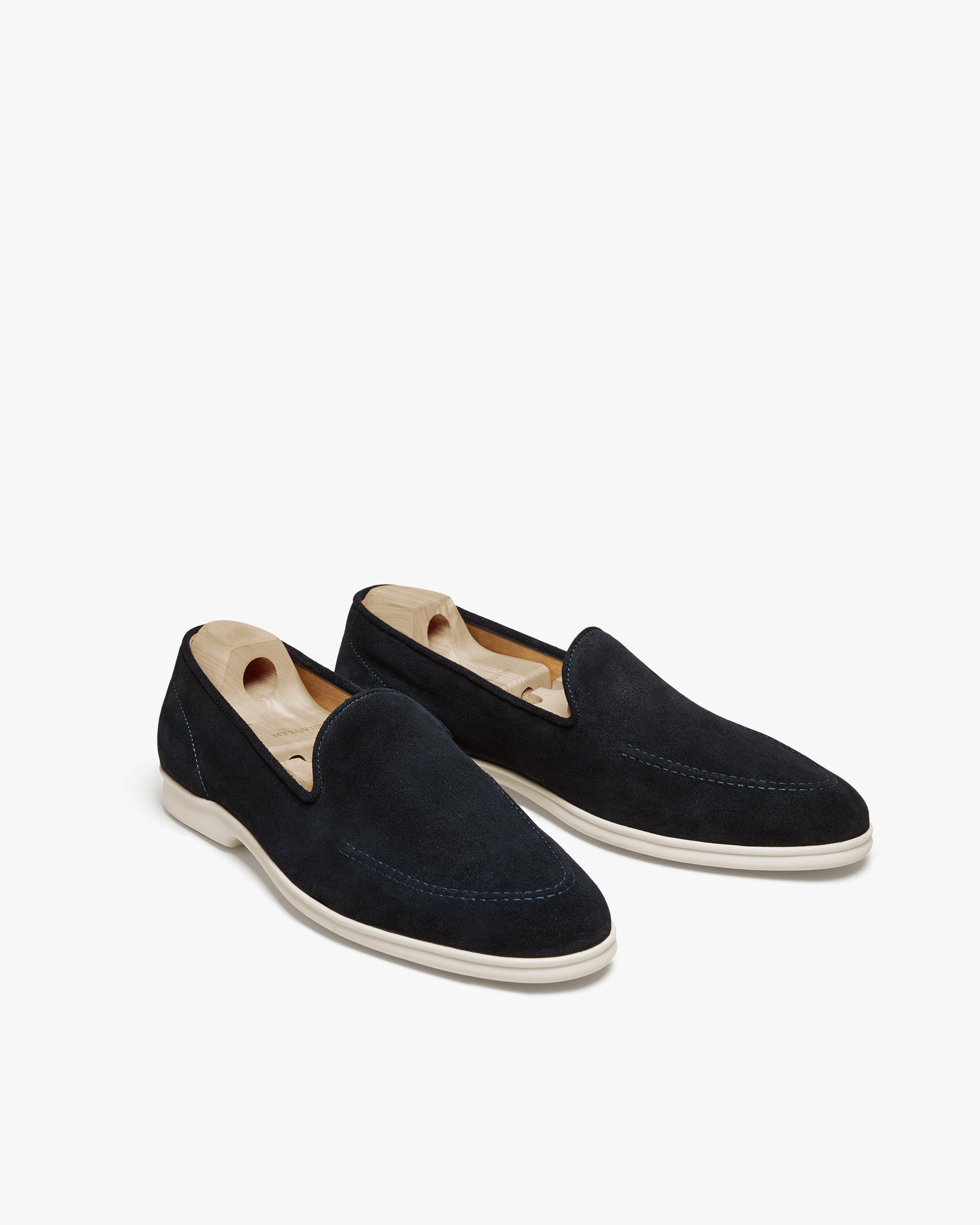 Brännö II in navy suede displayed at an angle, featuring soft suede uppers, tonal stitching, and white rubber soles, each loafer shaped with a wooden shoe tree.