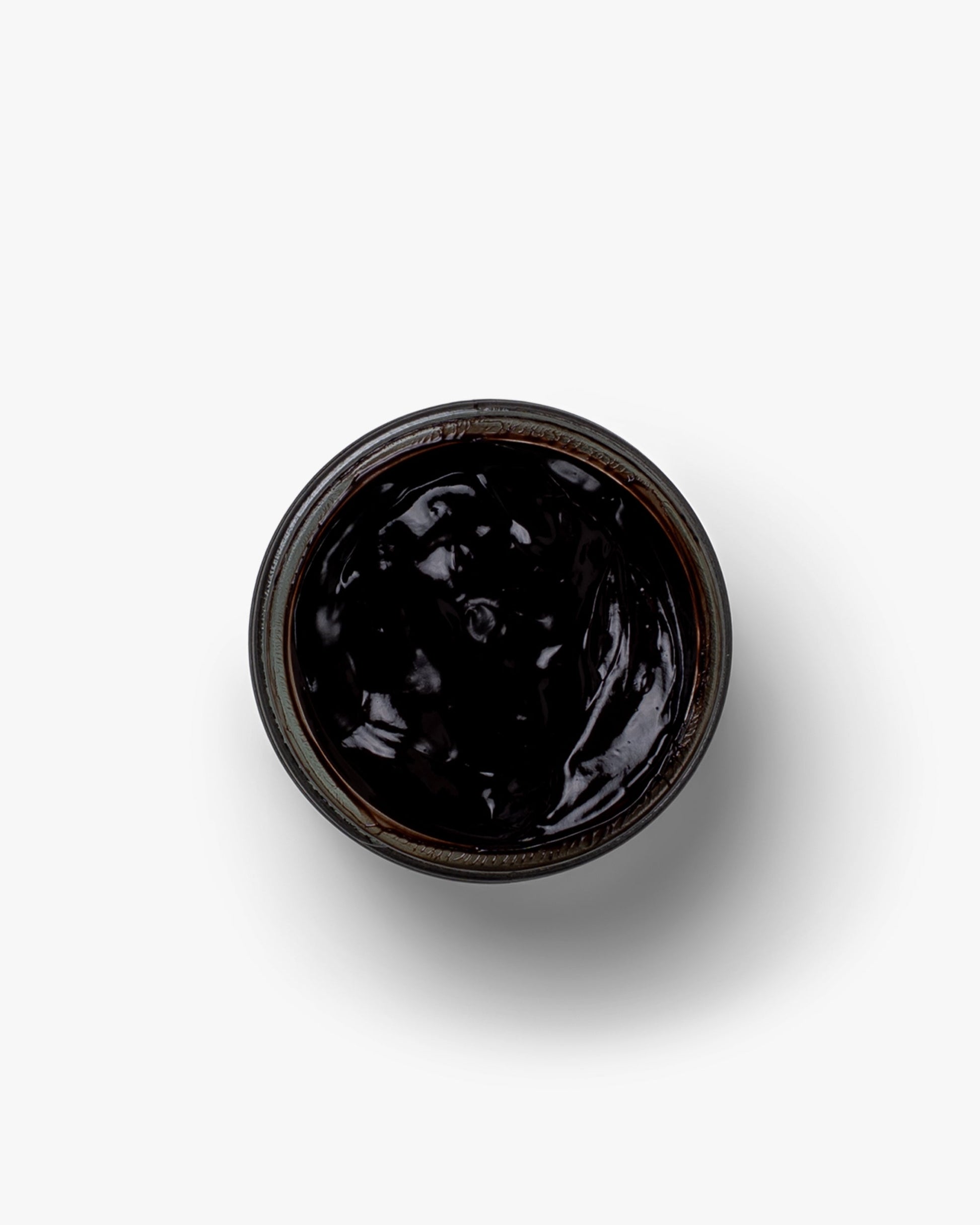 An open jar of Myrqvist Shoe Cream in black, showing its smooth, glossy texture designed to nourish and restore the appearance of leather shoes.