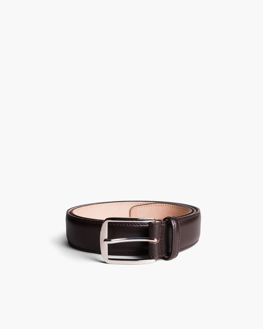 Men’s dark brown leather belt with a polished silver square buckle, featuring even stitching and softly contoured edges, styled in a coiled position against a white background.