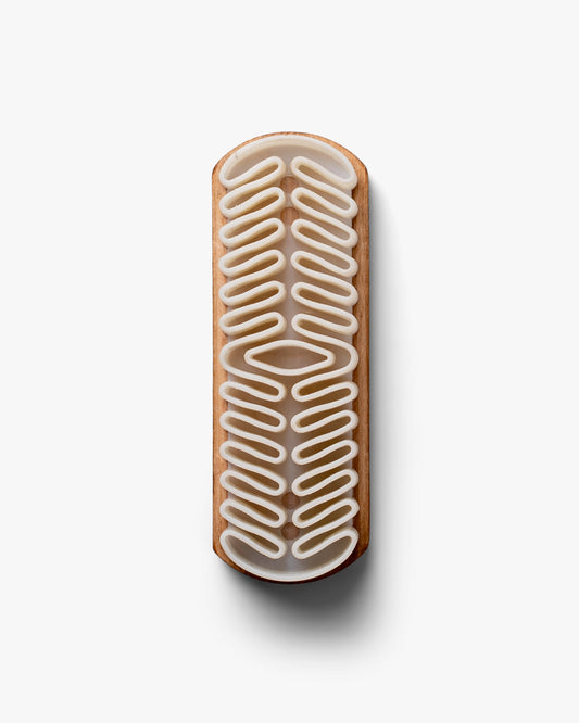 A top-down view of the Suede Brush – Crepe, detailing its wooden handle and textured crepe rubber head.