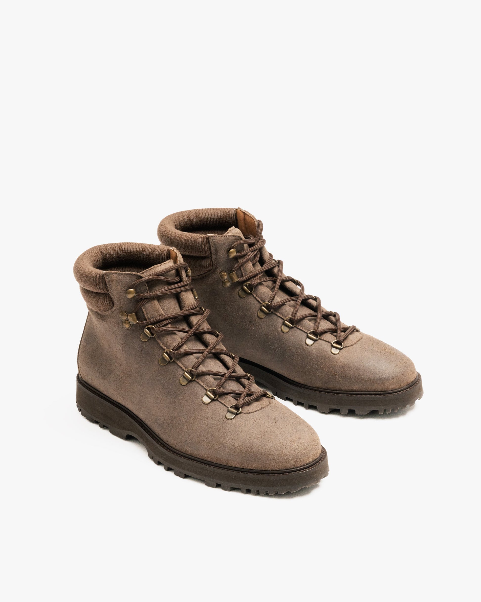Duved in taupe waxed suede features a clean hiking boot silhouette with a textured suede upper, brass-finished hardware, padded collar, and sturdy lug sole designed for both city and outdoor wear.