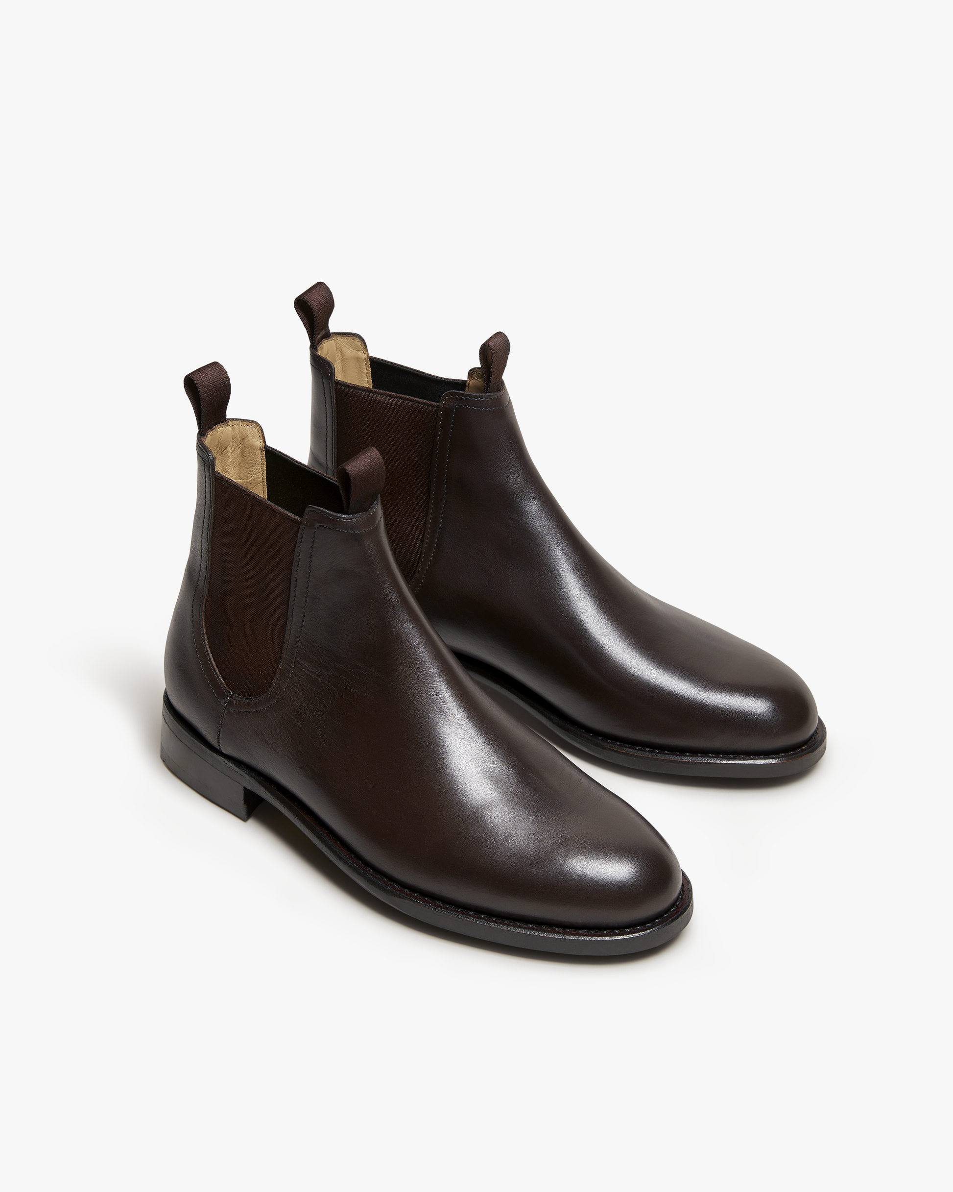 Elfvik Chelsea boots in dark brown calf leather with a sleek, polished finish, elastic side panels, and pull tabs, shown at an angle to highlight the refined silhouette and craftsmanship.
