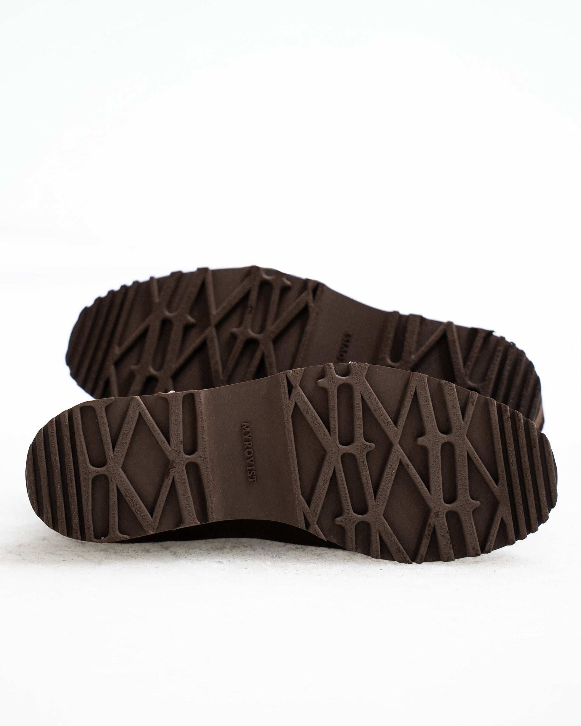 Close-up of the rugged, brown hiking sole on Duved in dark brown suede, showcasing deep tread patterns designed for traction and stability across varied terrain.
