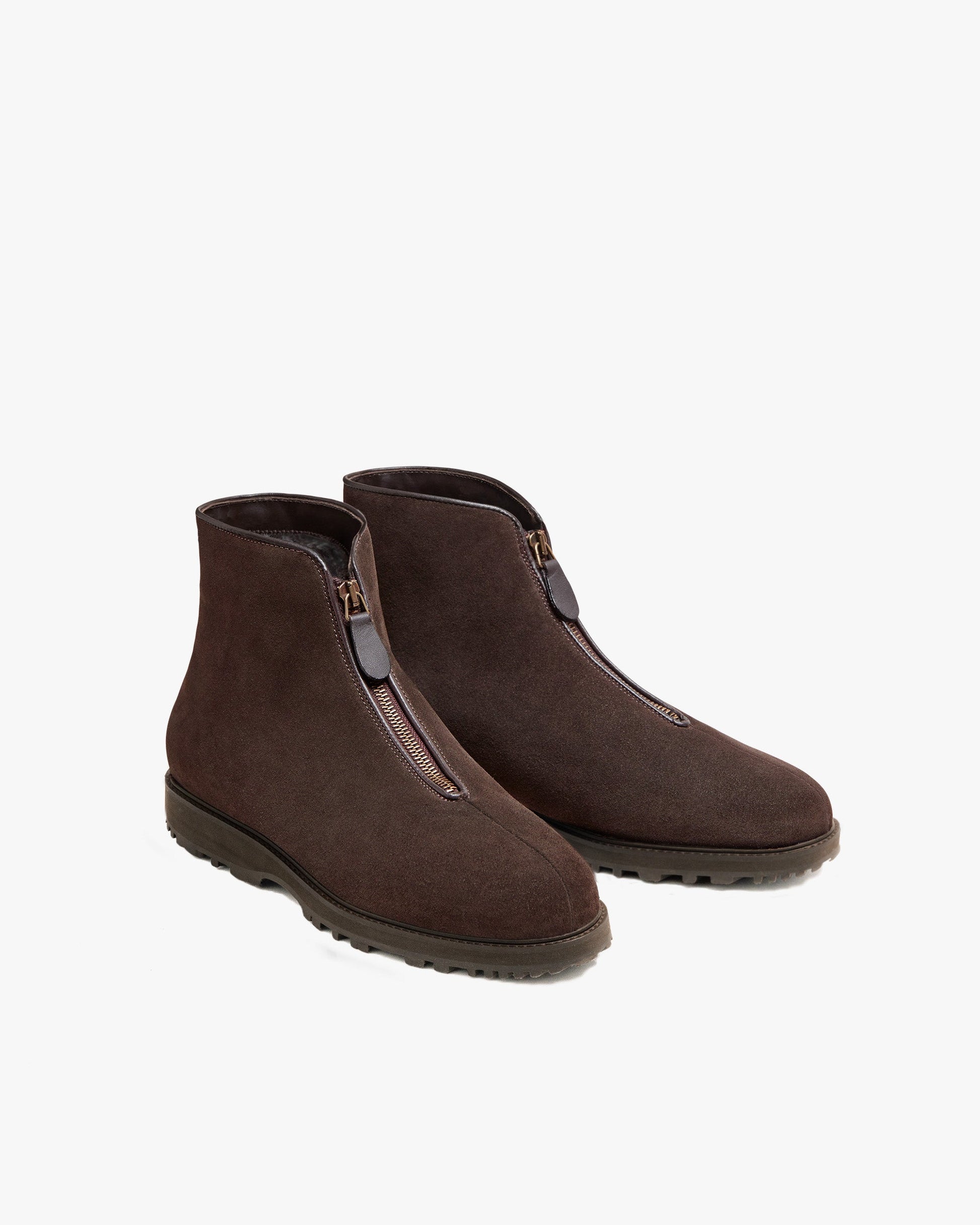 Pair of Funäs in dark brown suede, featuring a minimalist ankle boot design with central zipper closures and durable Explorer soles, ideal for winter wear with wool trousers, slacks, or dark denim. The soft suede finish and clean lines highlight the refined, versatile style.