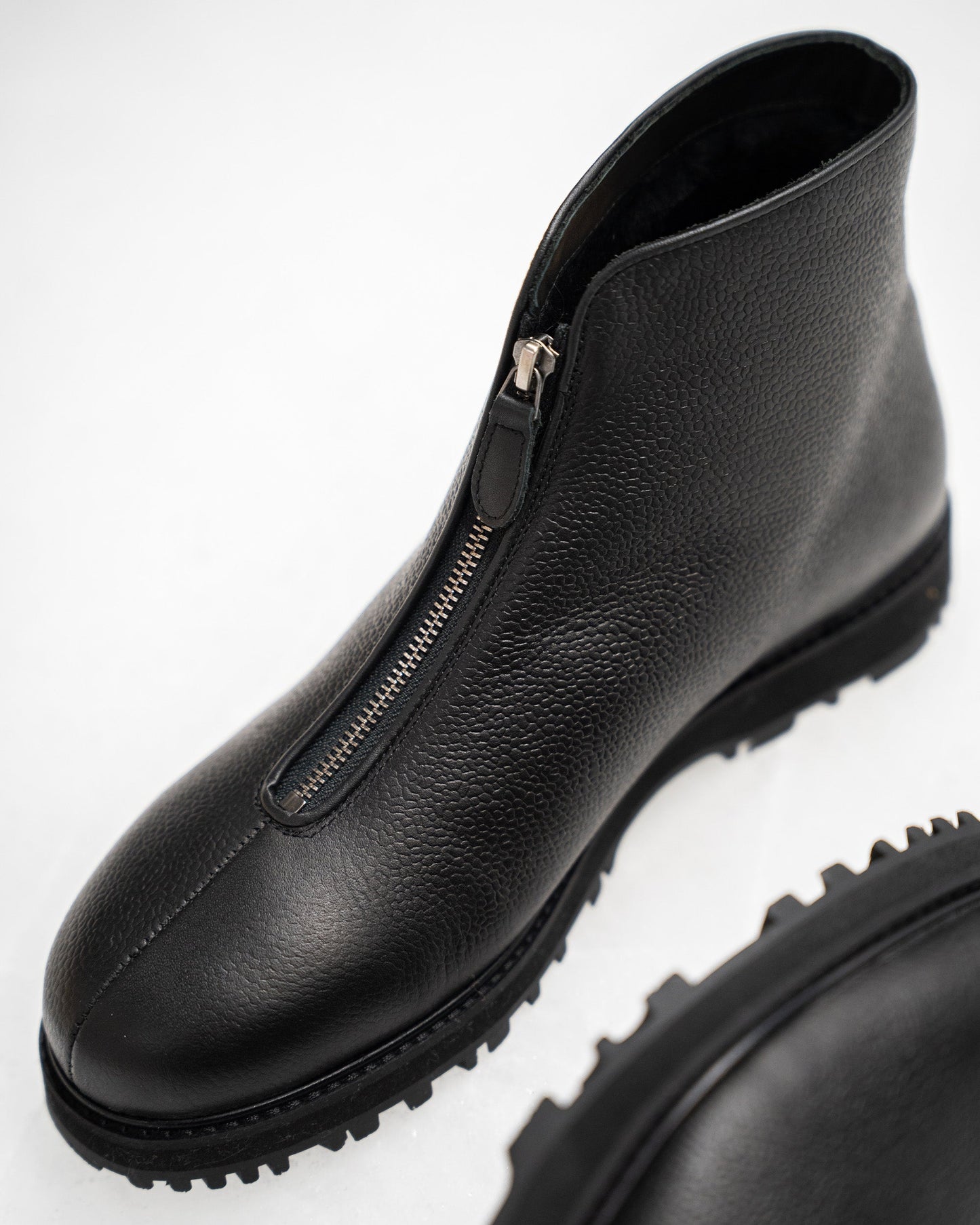 Funäs in black country calf features a close-up of the boot's textured full-grain leather, central zipper, and rugged Explorer sole, emphasizing its refined Scandinavian design and winter-ready construction.