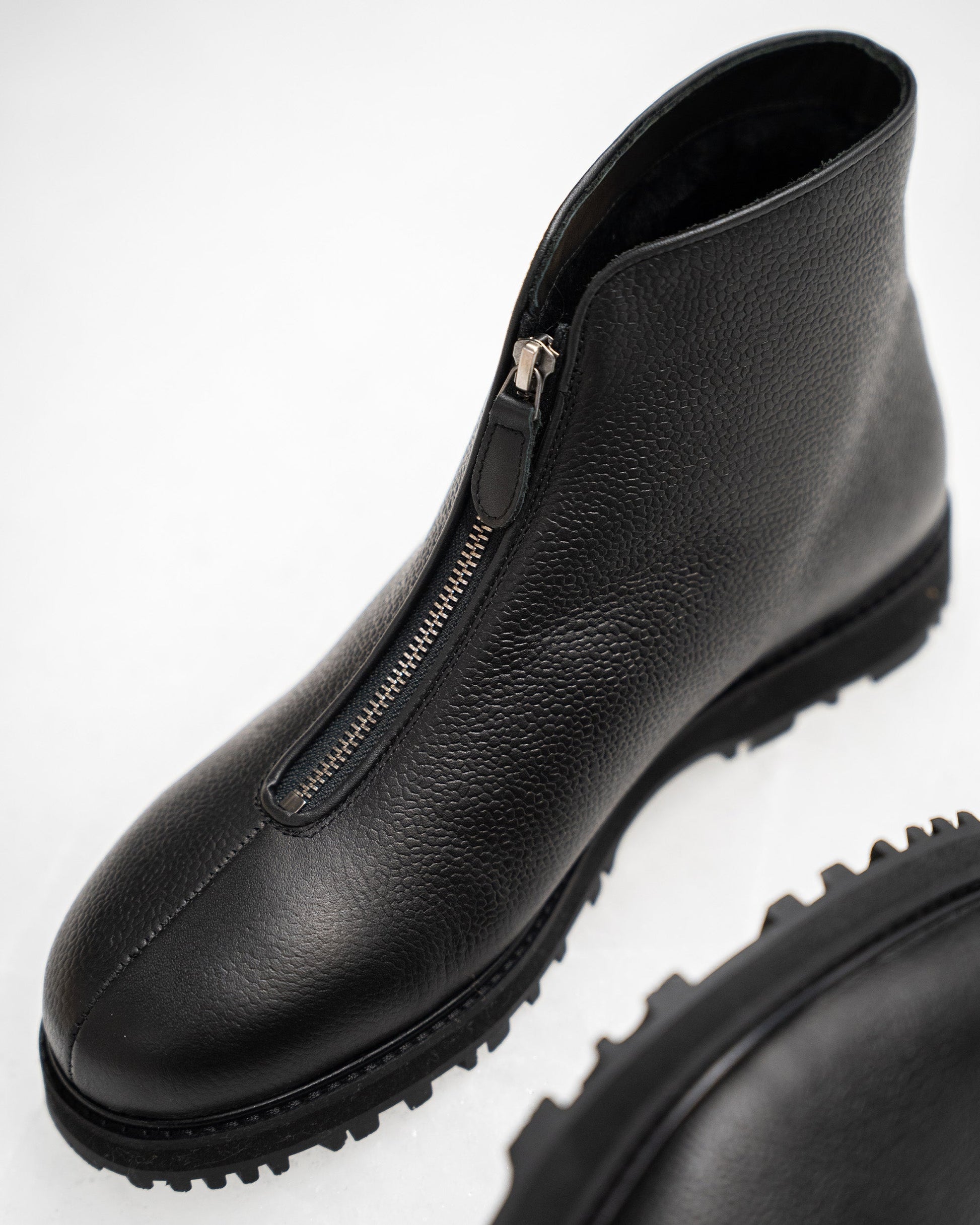 Funäs in black country calf features a close-up of the boot's textured full-grain leather, central zipper, and rugged Explorer sole, emphasizing its refined Scandinavian design and winter-ready construction.
