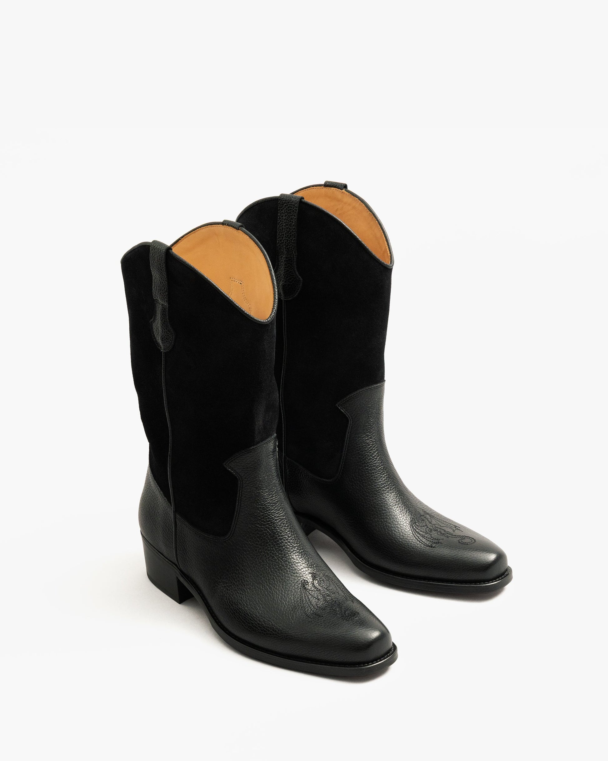 A three-quarter view of Karlslund – Fares Edition boots in black, featuring grained leather, a suede shaft, and dragon embroidery.