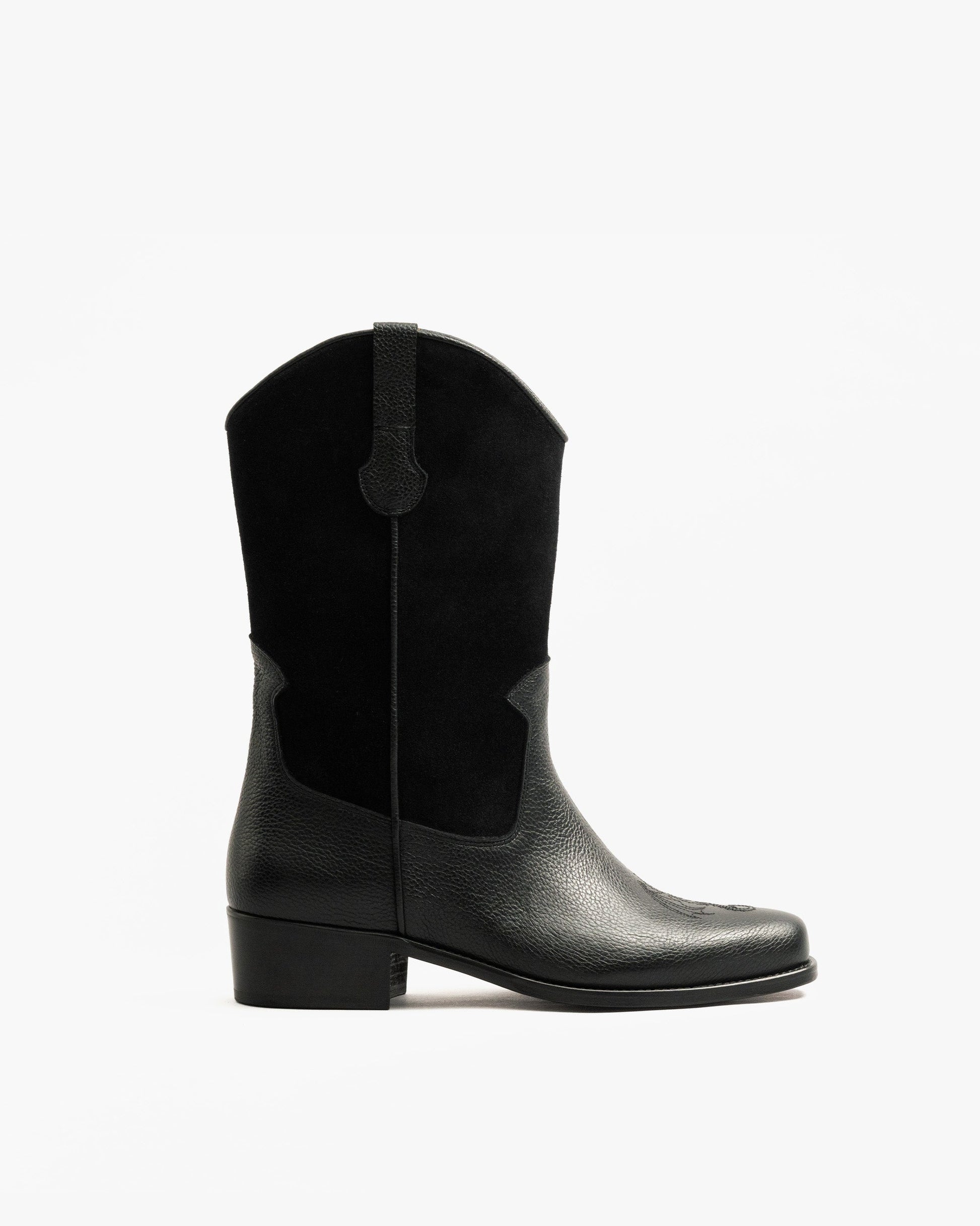 A side profile of the black Karlslund – Fares Edition boot, showcasing its western silhouette in grained leather and suede.