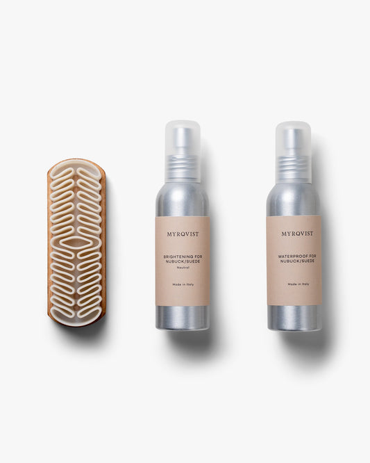 Shoe Care Kit – Suede featuring a sculpted crepe brush with a wooden handle, alongside minimalist bottles of brightening and waterproofing sprays, arranged on a clean white background.