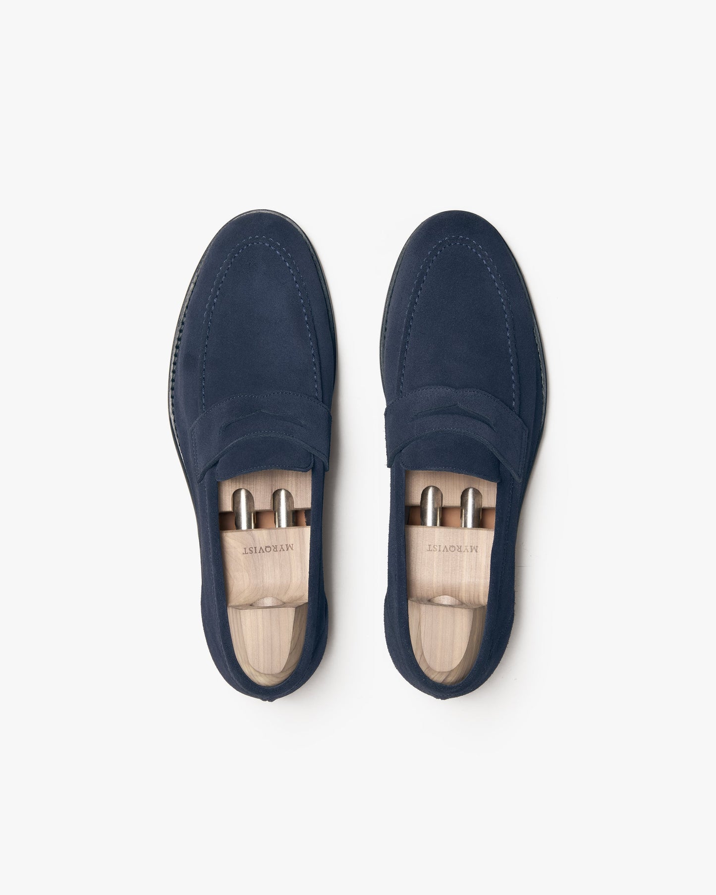 Lysekil II in navy suede shown from above, highlighting the deep blue suede, apron toe stitching, and classic penny strap design with wooden shoe trees inside each loafer.