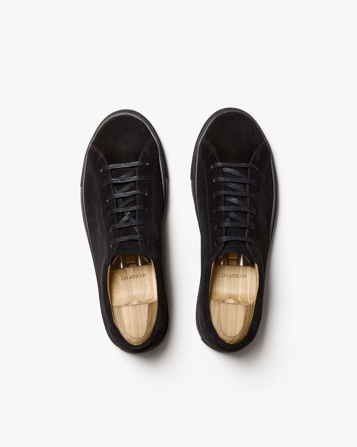 Pair of Oaxen Monochrome in black suede viewed from above, showcasing the seamless monochrome design, tonal laces, matte suede texture, and wooden shoe trees inside each sneaker.