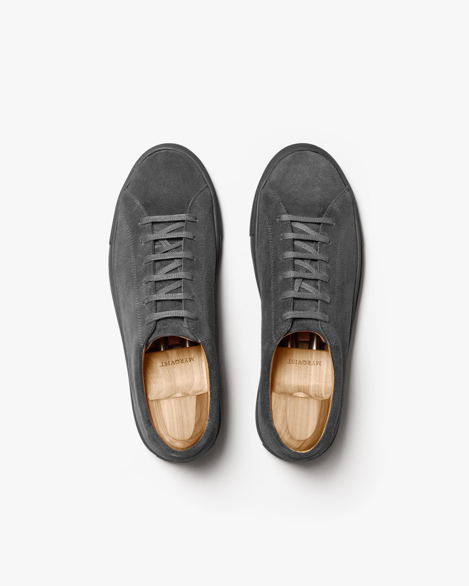 Pair of Oaxen Monochrome sneakers in dark grey suede shown from above, highlighting the clean lines, tonal laces, and seamless construction with wooden shoe trees inside.