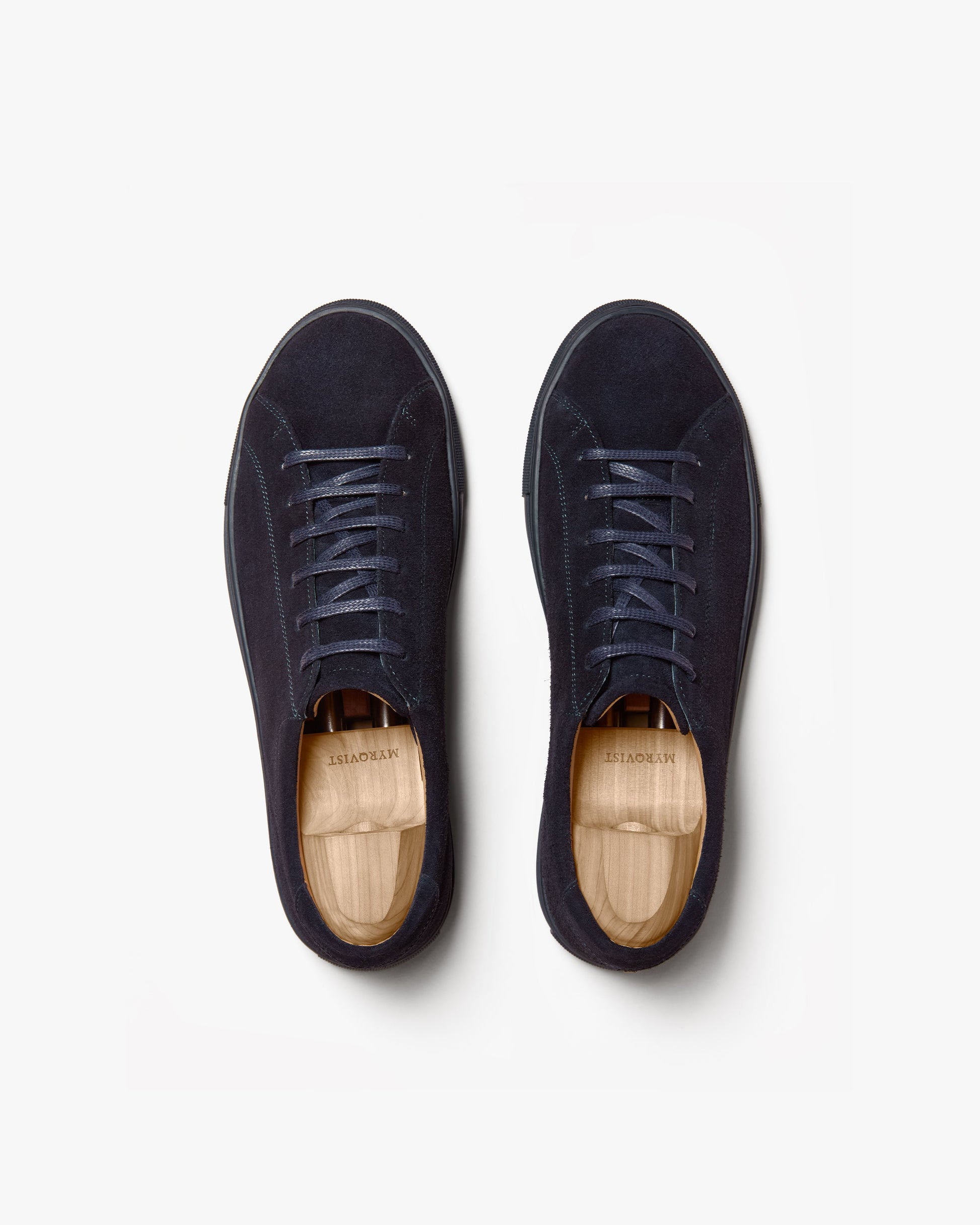 Pair of Oaxen Monochrome in navy suede shown from above, highlighting the seamless monochrome design, matching laces, and wooden shoe trees inside each sneaker.
