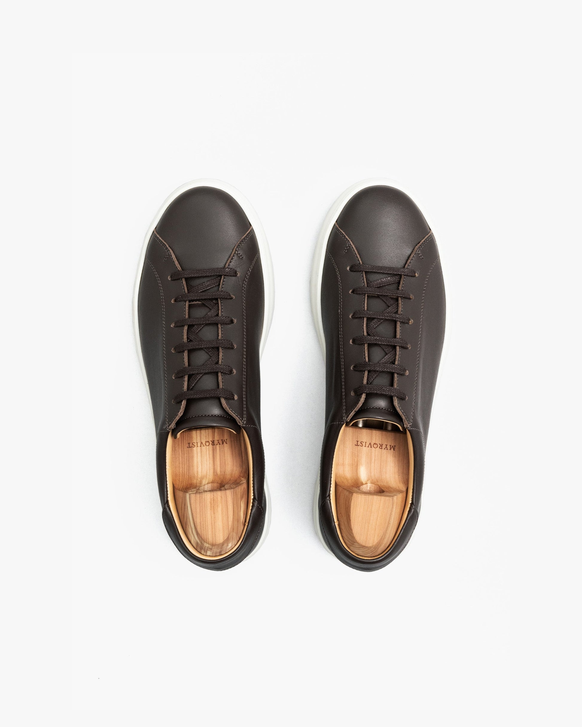 A pair of Oaxen in dark brown calf shown from above, highlighting the smooth brown leather, clean stitching, and white rubber soles, each shoe fitted with a wooden shoe tree.