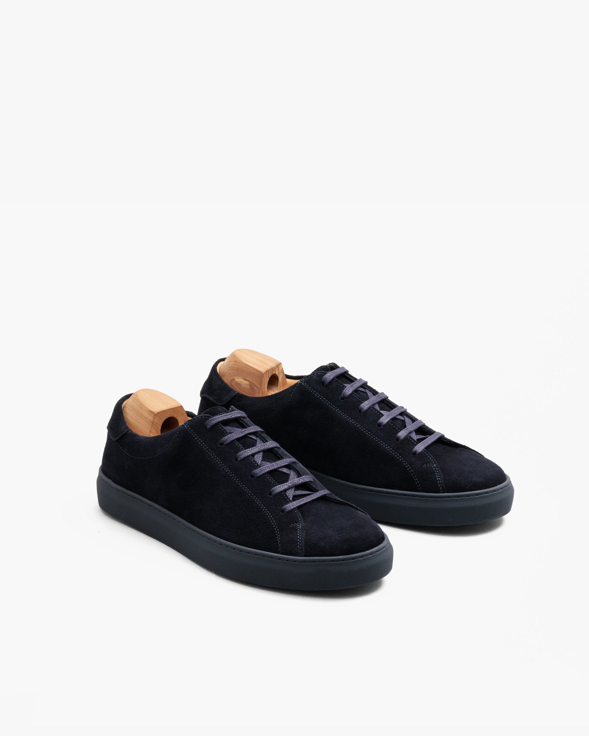 Oaxen Monochrome in navy suede displayed at an angle, featuring a monochrome suede upper, matching laces, color-coordinated sole, and wooden shoe trees inside each sneaker.