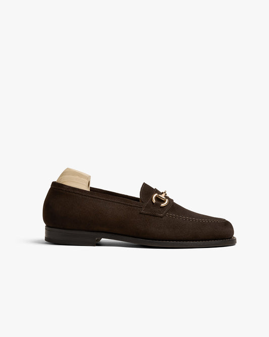 Karlberg loafer in dark brown suede featuring a gold-toned horsebit detail, rounded toe, and fine stitching, shown with a wooden shoe tree and a low stacked heel.