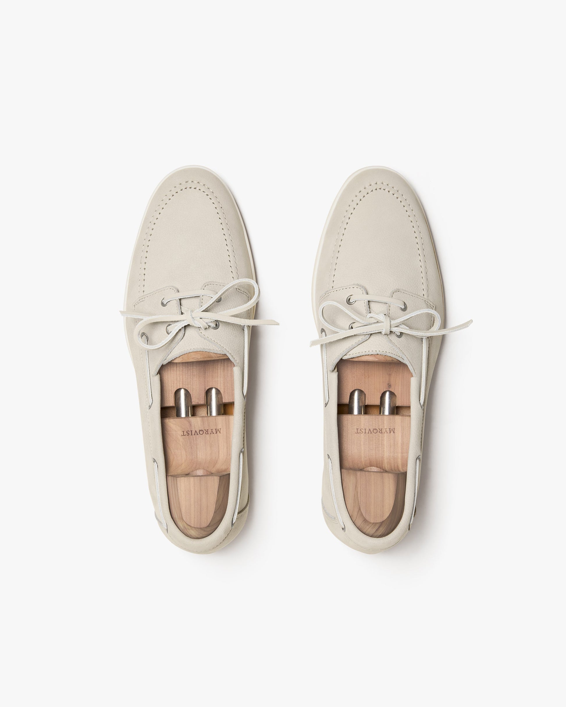 Sandhamn in beige nubuck shown from above, highlighting the soft nubuck upper, hand-stitched seams, minimalist lacing, and included wooden shoe trees for maintaining shape and structure.