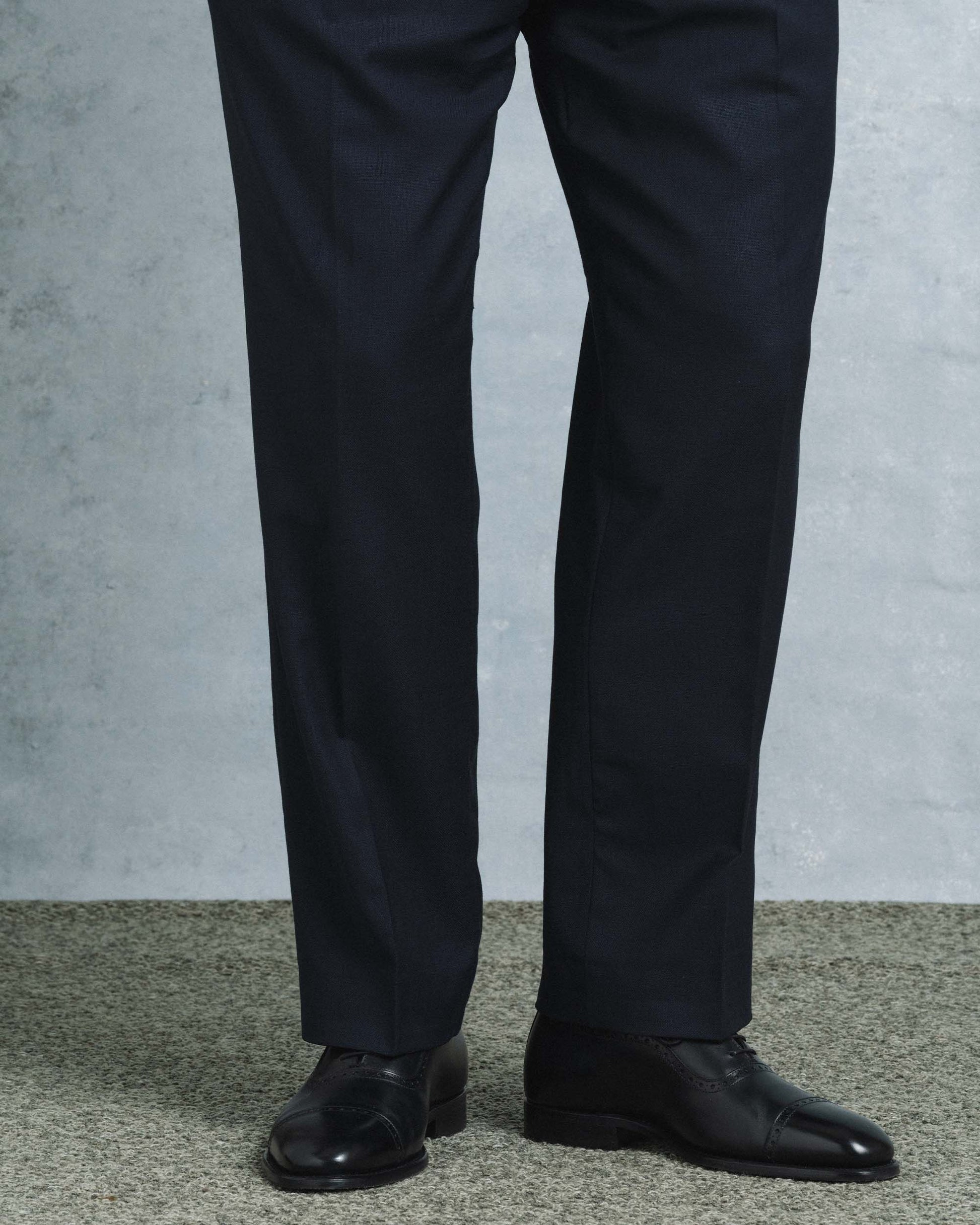 Skytteholm II in black calf worn with tailored dark dress trousers, highlighting the Oxford shoe's polished finish, closed lacing, and subtle brogue cap toe in a formal setting.
